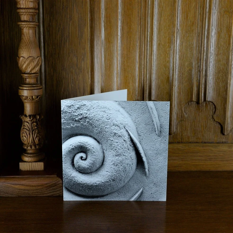 Spiralfish Wave and Tide greetings card standing on a wooden mantelpiece
