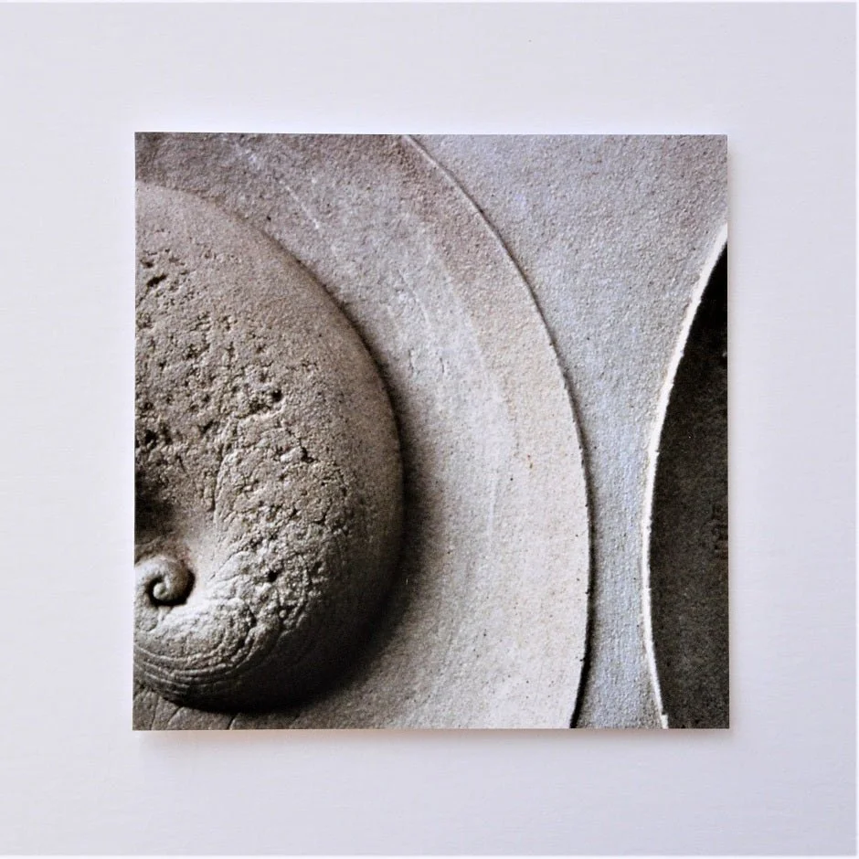 Soundwave greetings card, a photograph of a carved stone relief with a curved wave and spiral