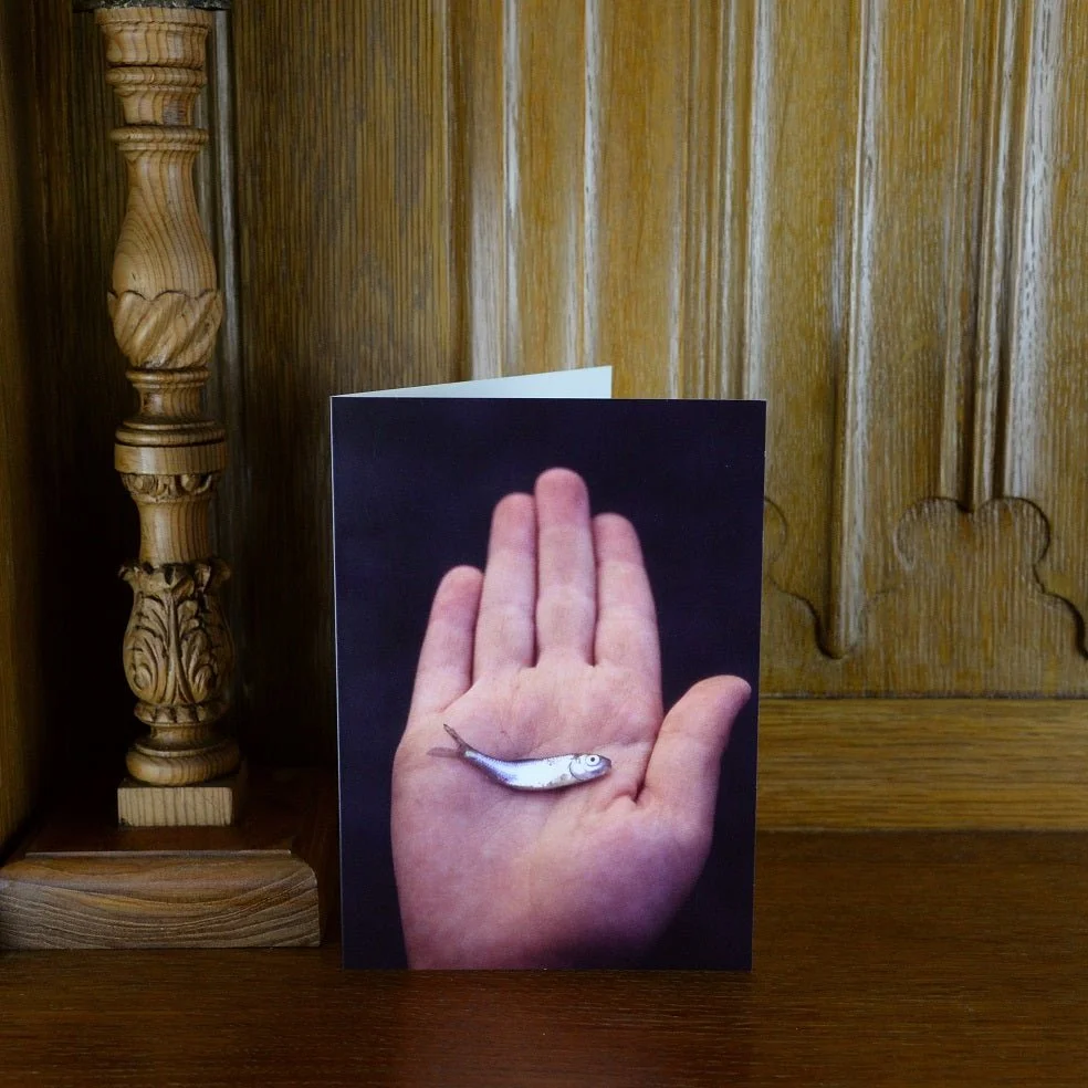 One Silvery Fish vertical greetings card standing on a wooden mantelpiece