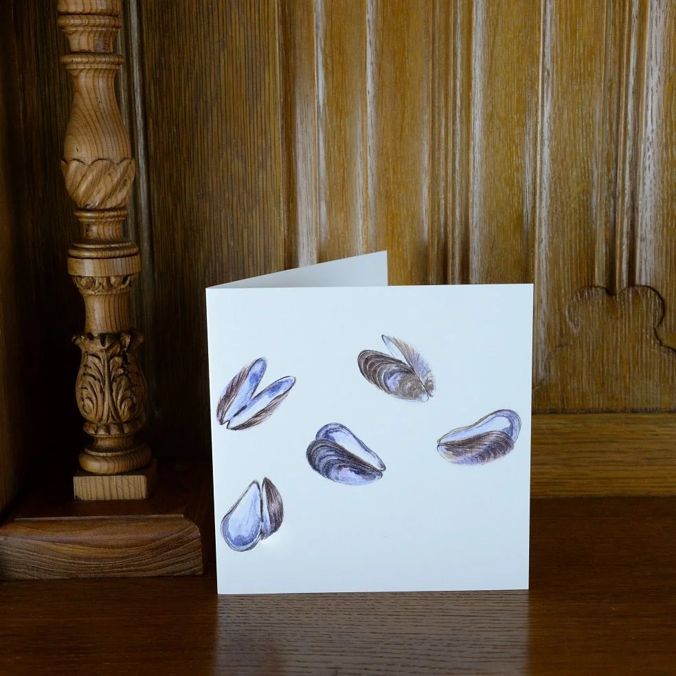 Mauve Mussels of the Sea greetings card standing on a wooden mantelpiece