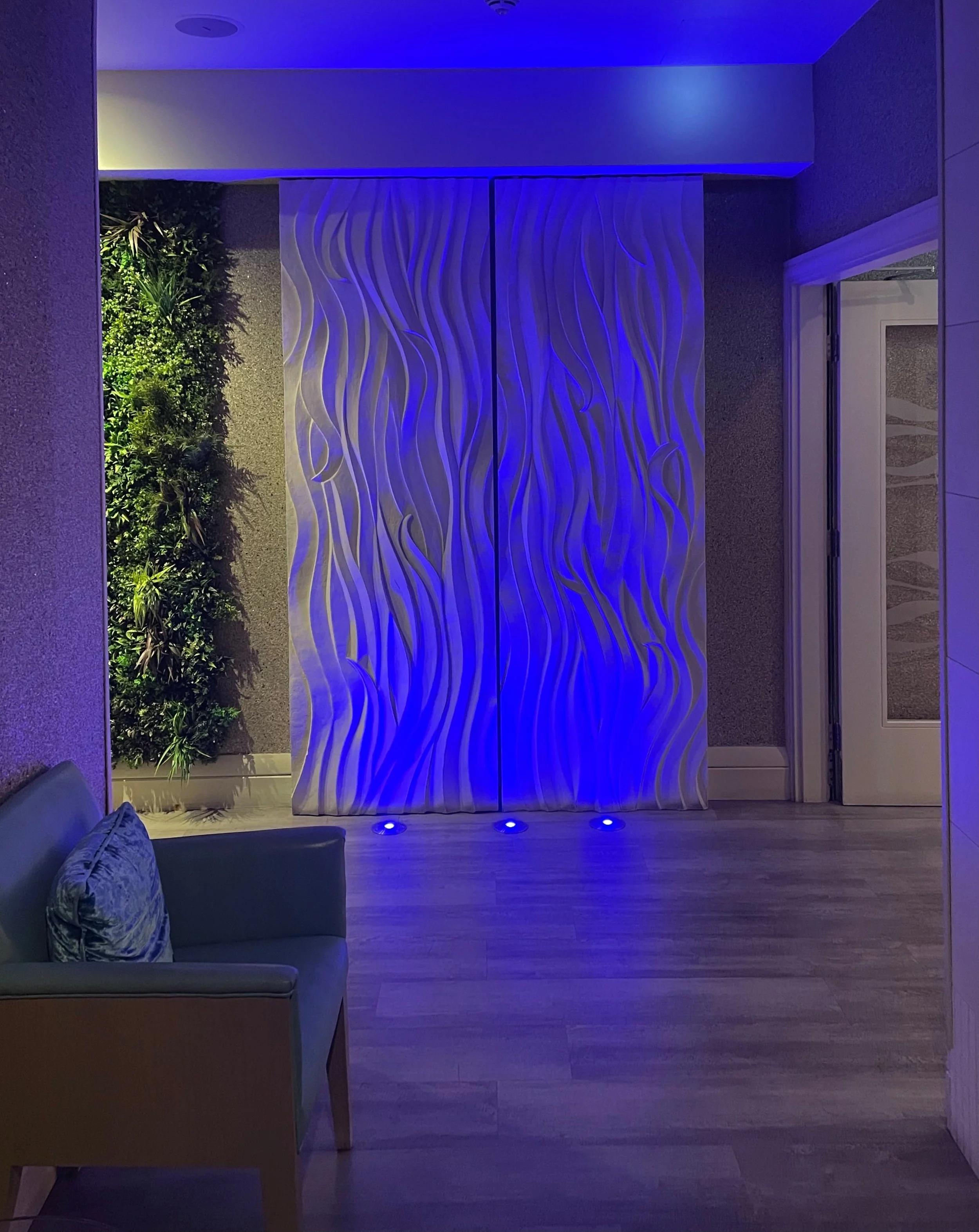 Smooth Sand Ripple wall panel washed in blue light along a corridor with seating