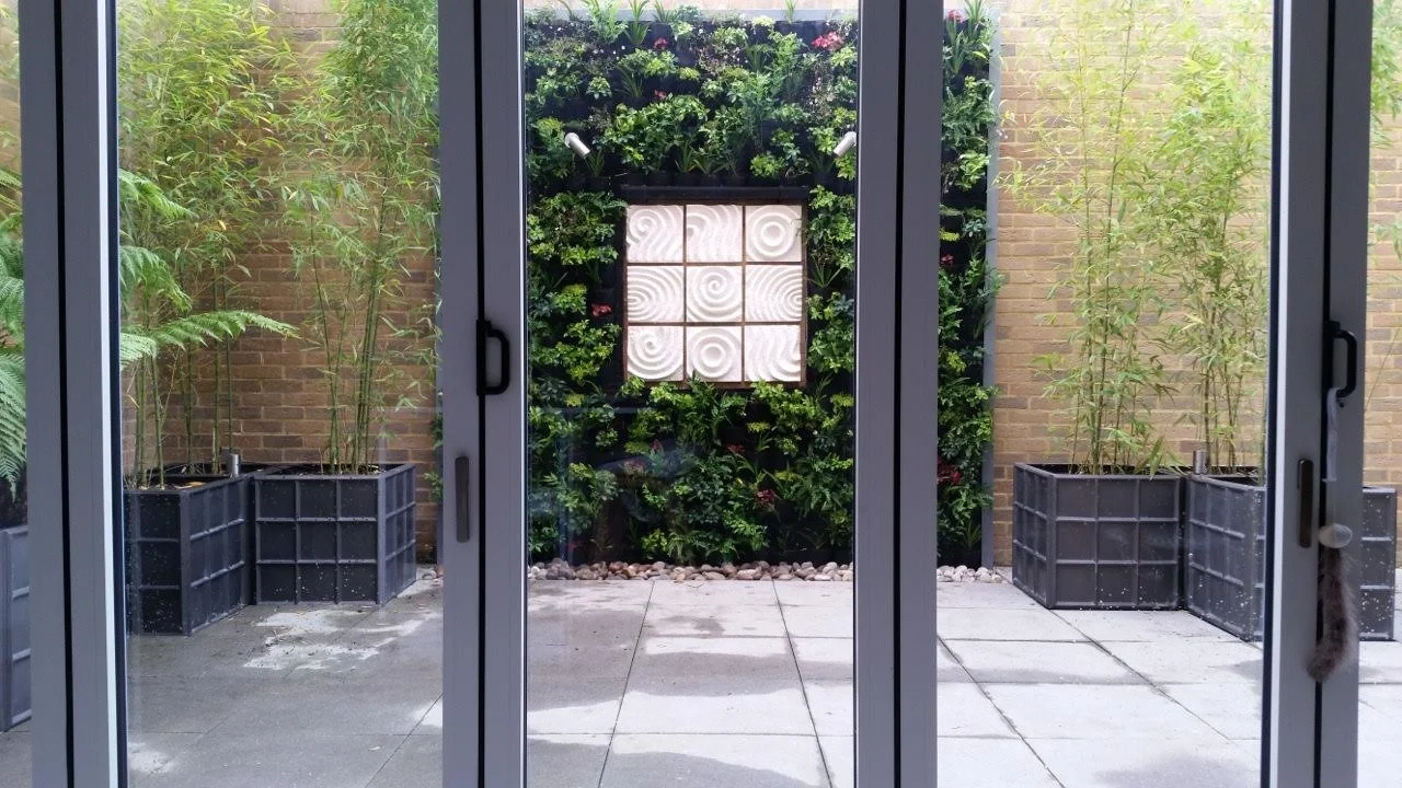 Japanese Raked Water Path wall sculpture on a courtyard wall beside patio doors and climbing greenery