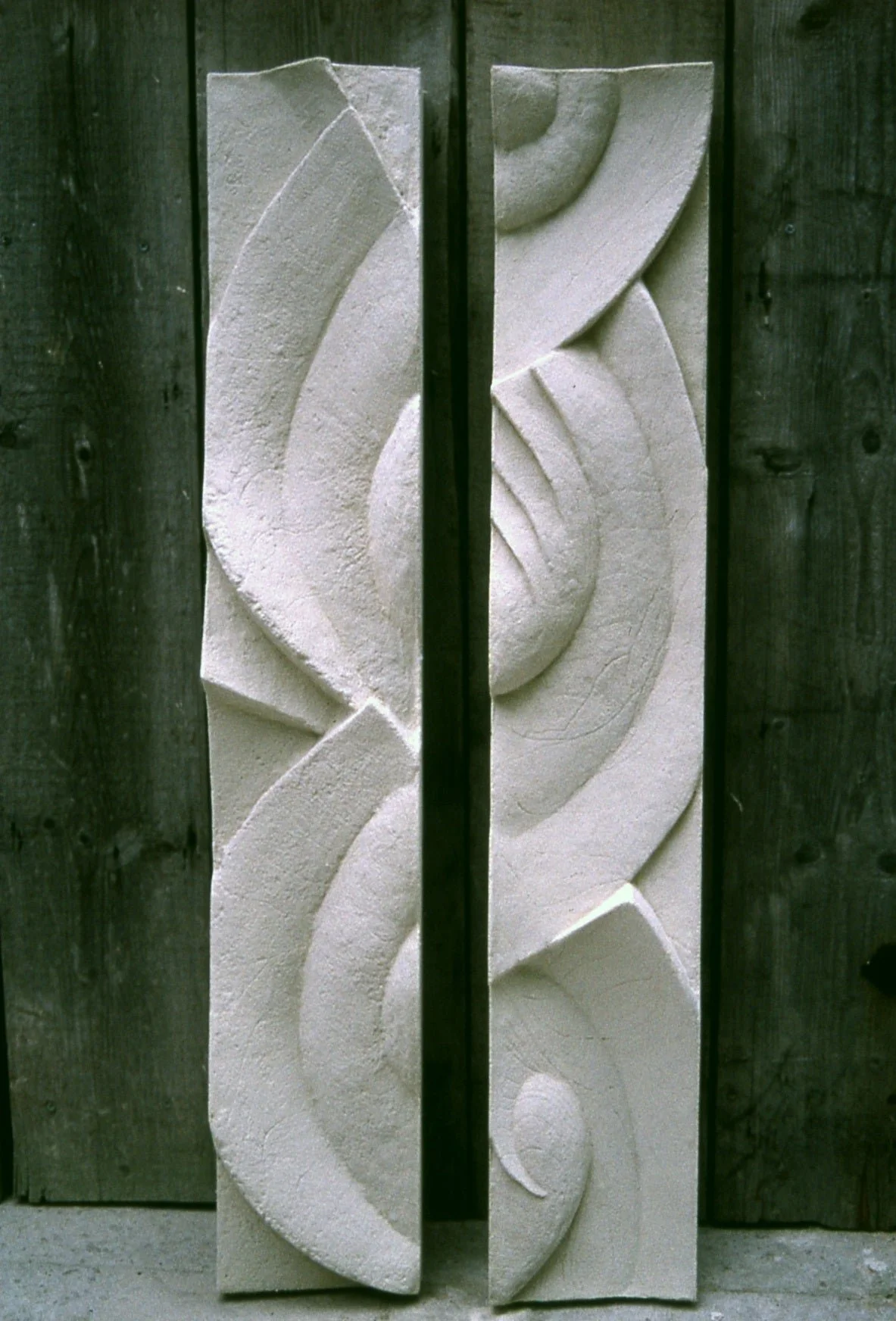 Three Frozen Decowaves wall sculpture on a dark green wall, the carved waves lit from the side