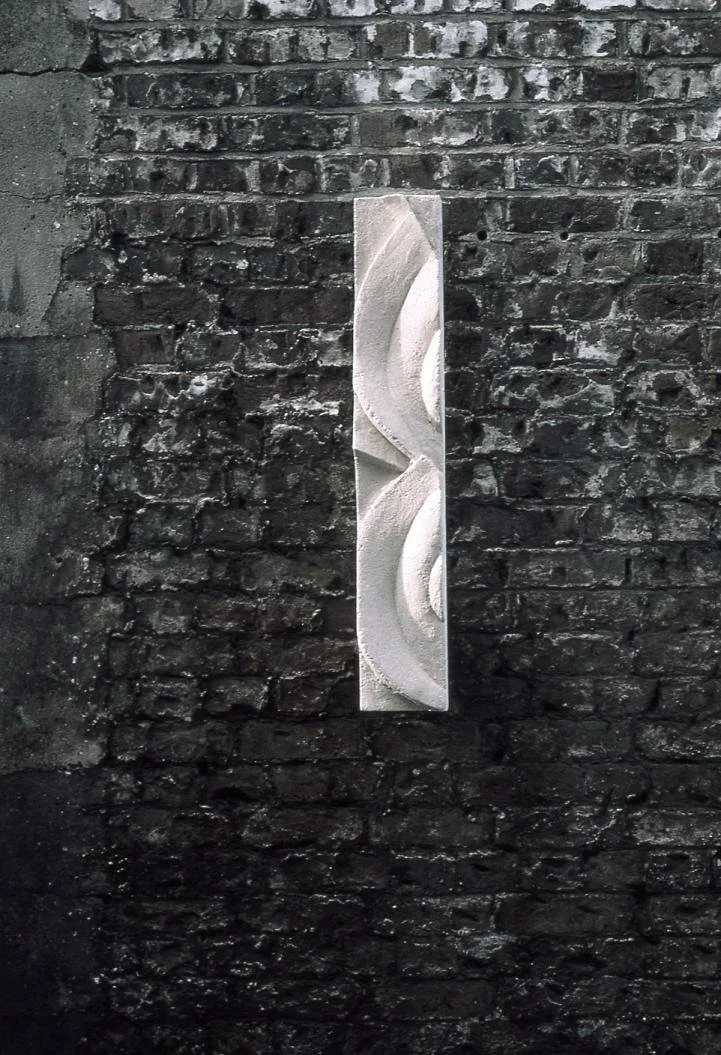 A single Frozen Decowave panel mounted vertically on a dark brick wall