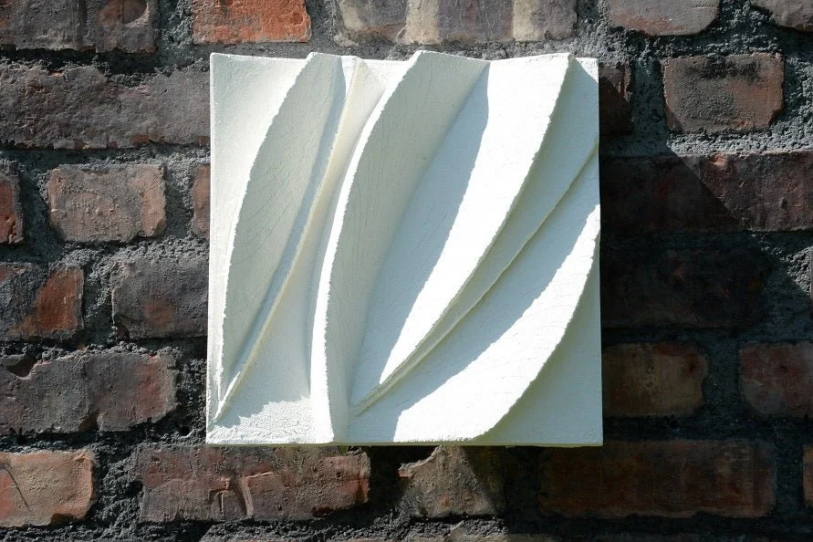 Two Leaf Forms wall sculpture, a single white panel of carved leaf blades mounted on dark brick