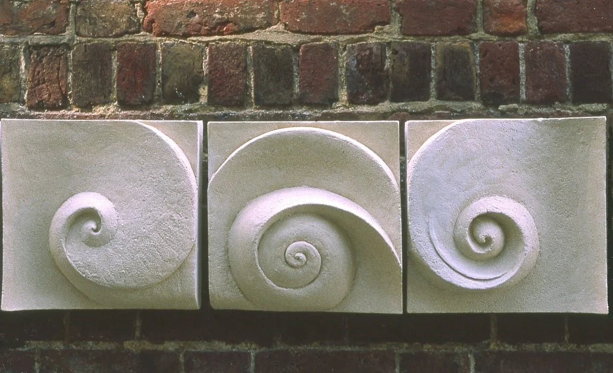 Moonphases Three wall sculpture, three carved spiral panels mounted in a line on an old brick wall
