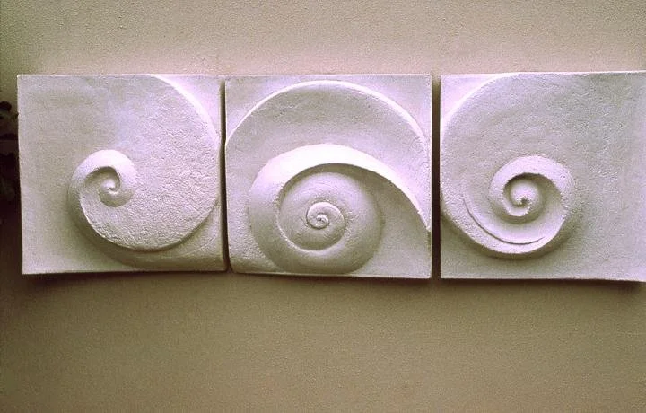 Close view of the Moonphases Three wall sculpture showing the three carved spirals lit from the side