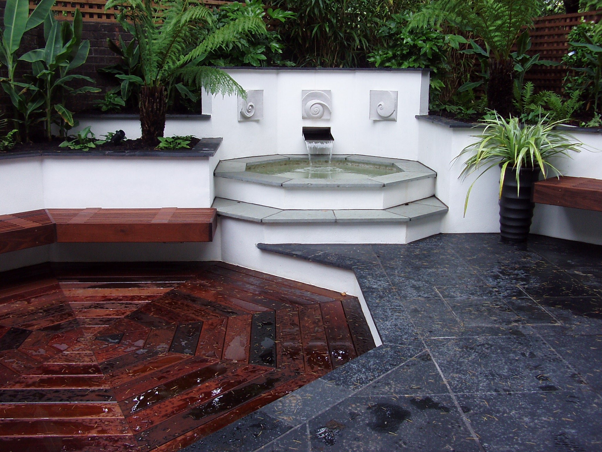 Moonphases Three wall sculpture in a tropical planted courtyard with a slate terrace and water feature
