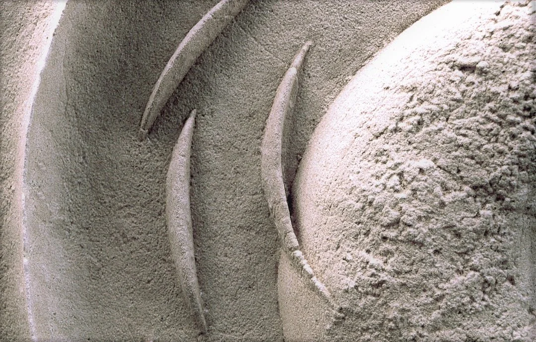 Close detail of the Spiralfish Wave and Tide wall sculpture showing its coarse stone surface and curved blade
