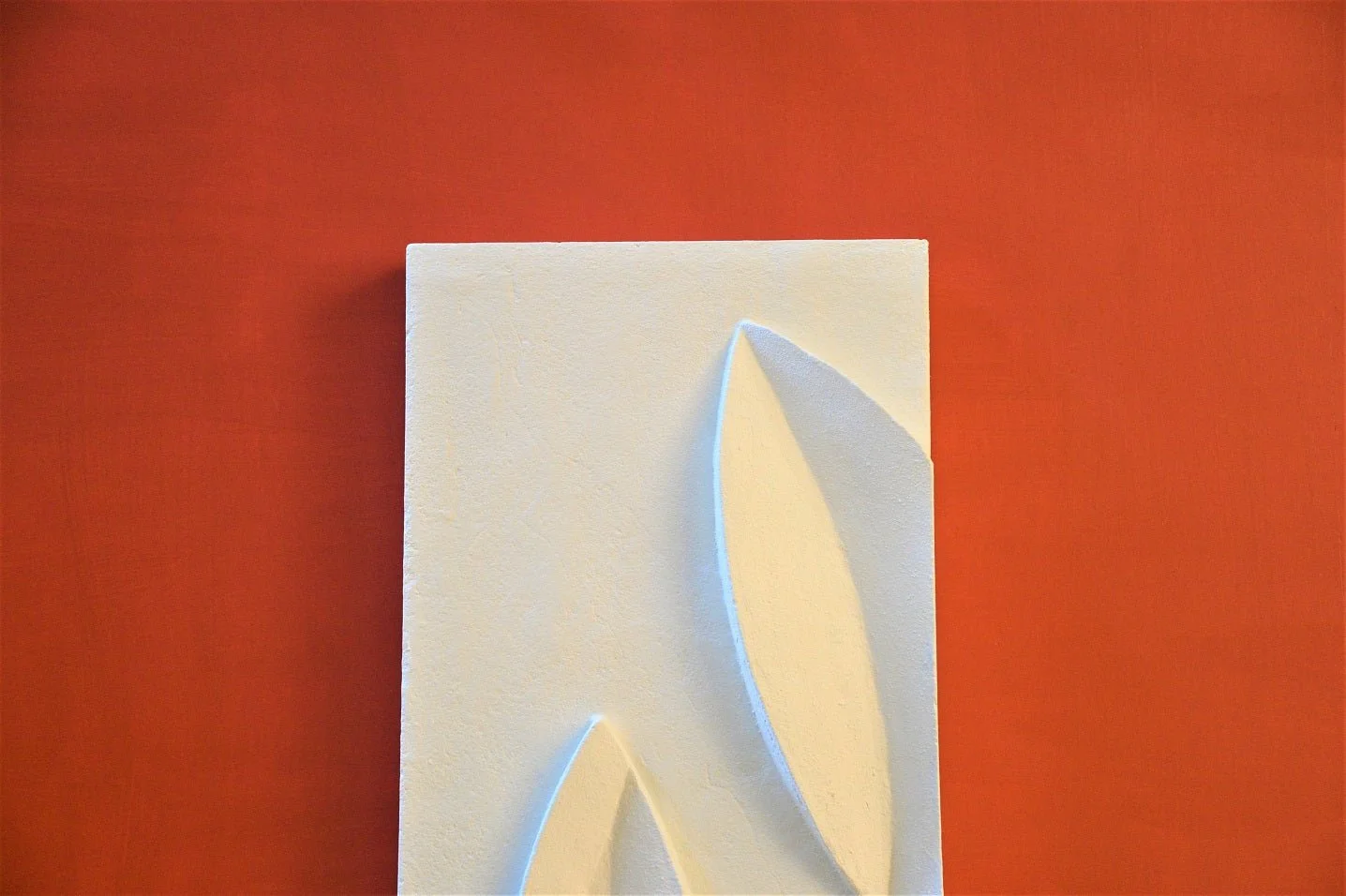 Magnolia Leaves wall sculpture seen at an angle, showing the depth of the panel against a terracotta wall
