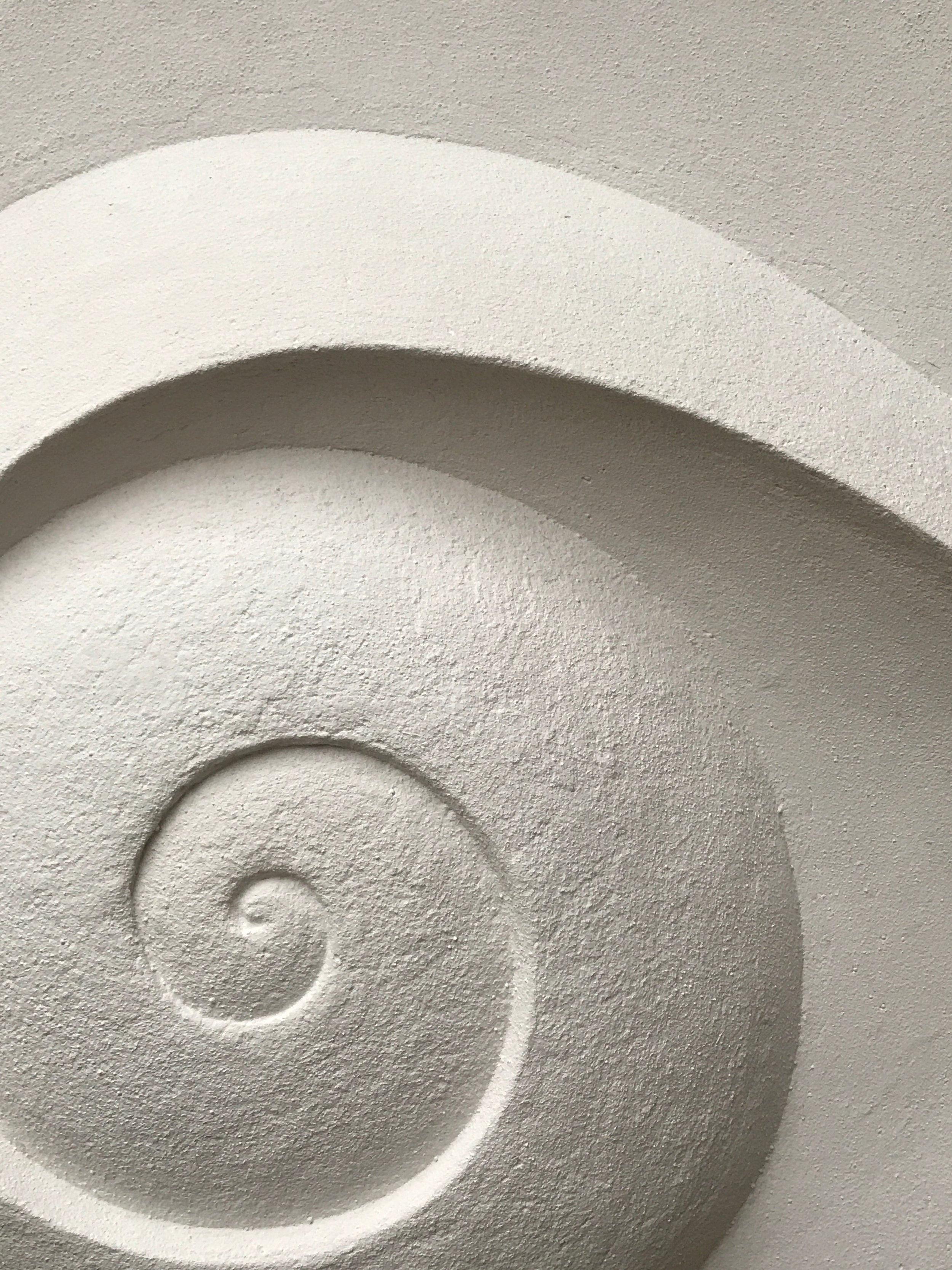 Close view of the Moonspiral wall sculpture showing the coiled centre of the carved spiral