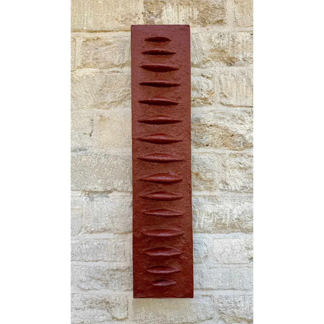 Frozen Fish wall sculpture in terracotta-effect gypsum composite, a tall ribbed panel like a fish spine, on pale stone