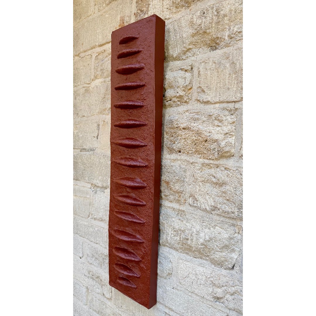 Frozen Fish wall sculpture seen at an angle, its terracotta-effect ribs casting a row of shadows