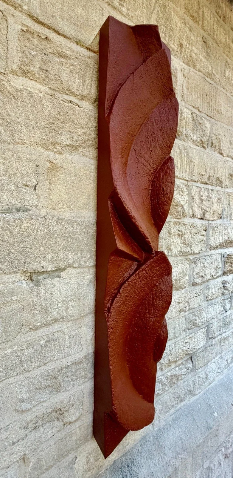 Frozen Deco wall sculpture, its slender terracotta-effect column folding in on itself against pale stone