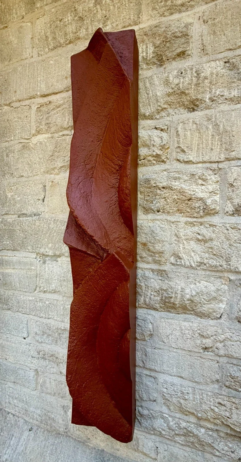 Angled view of the Frozen Deco wall sculpture, the terracotta-effect surface catching raking light