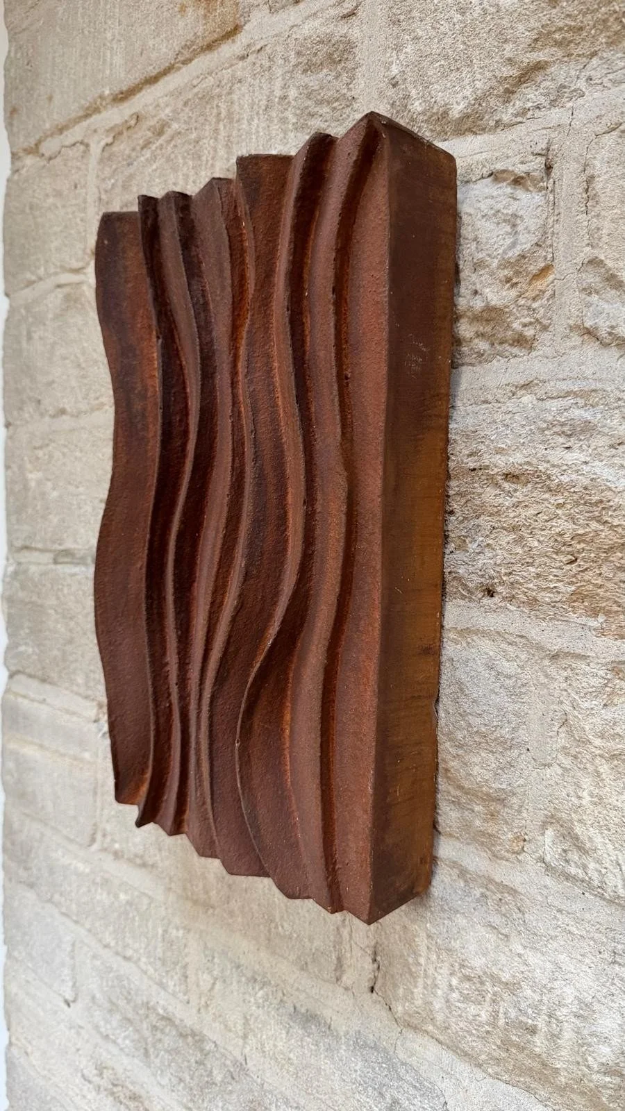 Close view of the faux rust wave relief wall sculpture showing its carved crests and painted rust patina