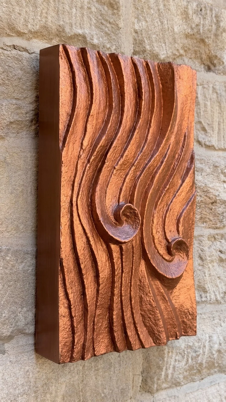 Angled view of the copper wave relief wall sculpture showing the depth of its carved, curling wave crests
