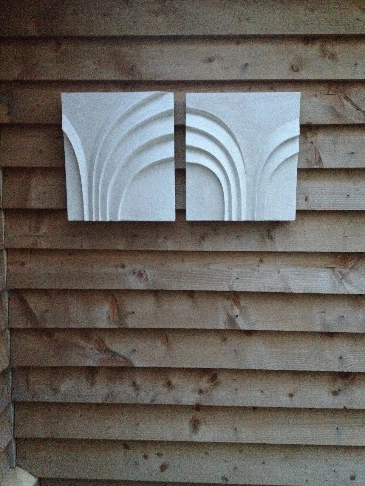 Palm Form One wall sculpture shown as a two-part pale stone relief on a timber clad wall