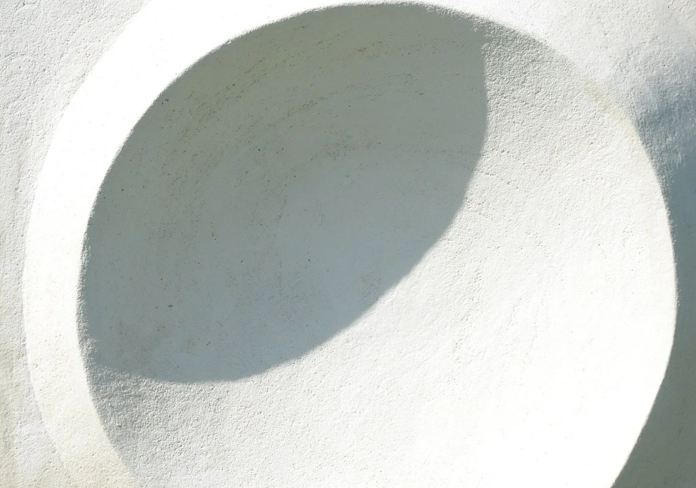 Close-up of the Moonwater wall sculpture concave stone surface showing its speckled texture and soft shadow