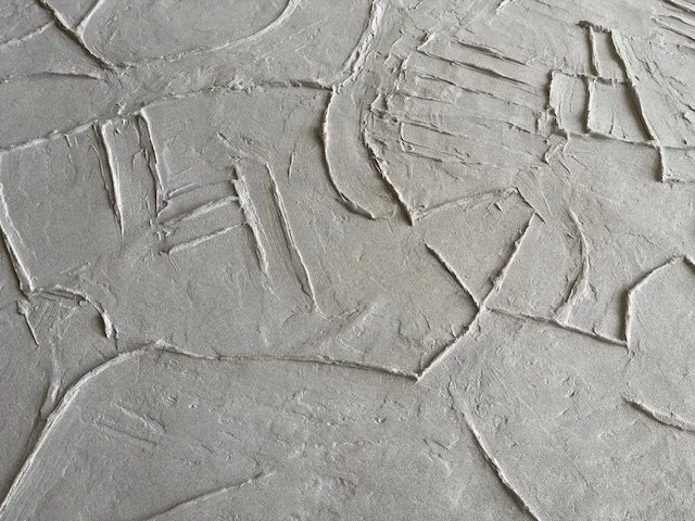 Angled detail of the white Icarus relief showing intersecting geometric marks.