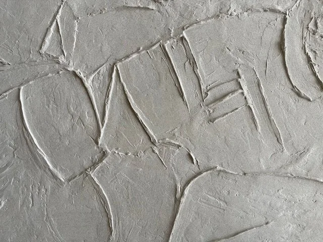 White Icarus relief detail with curved outlines and short, ladder-like raised marks.