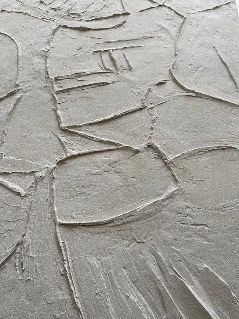 Vertical detail of the white Icarus relief, with rough texture and short raised lines.