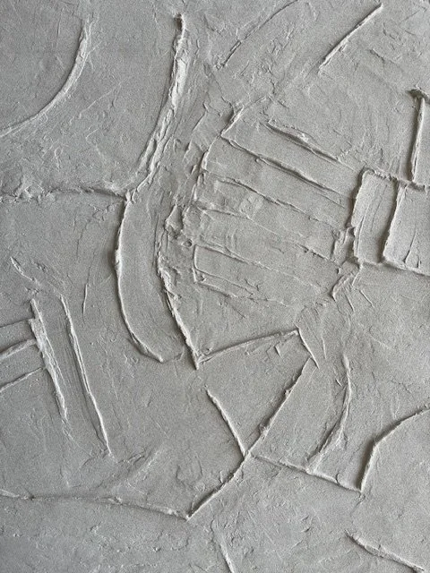 White Icarus relief detail with parallel raised bars and sweeping curved lines.