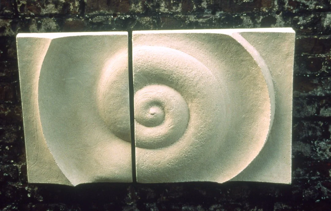 Paired white Bone Spiral panels on brick, with sunlight and shadows defining the spiral.