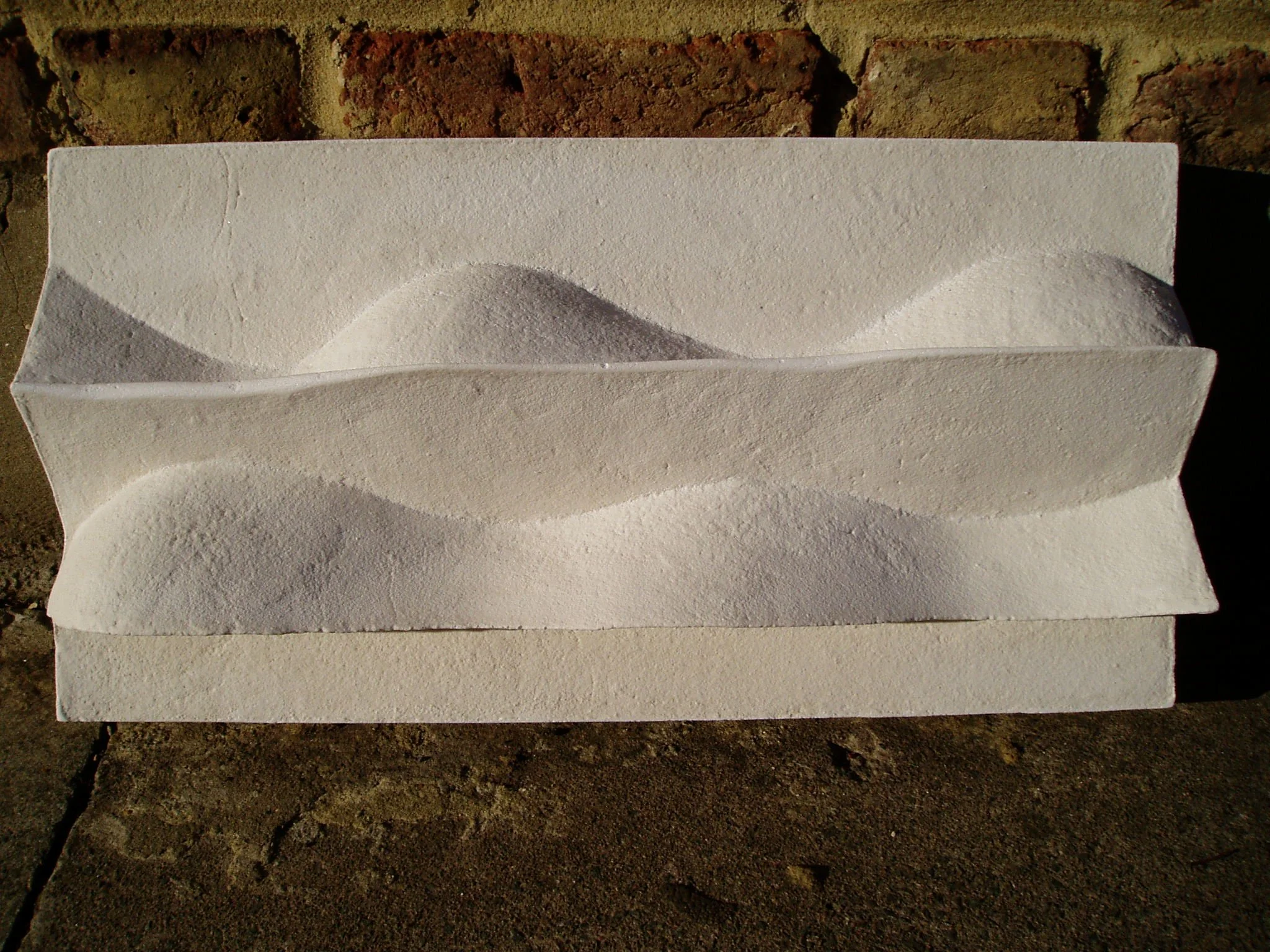 Horizontal view of the white Brancusi 2 relief, showing its sculpted wavy ridges.