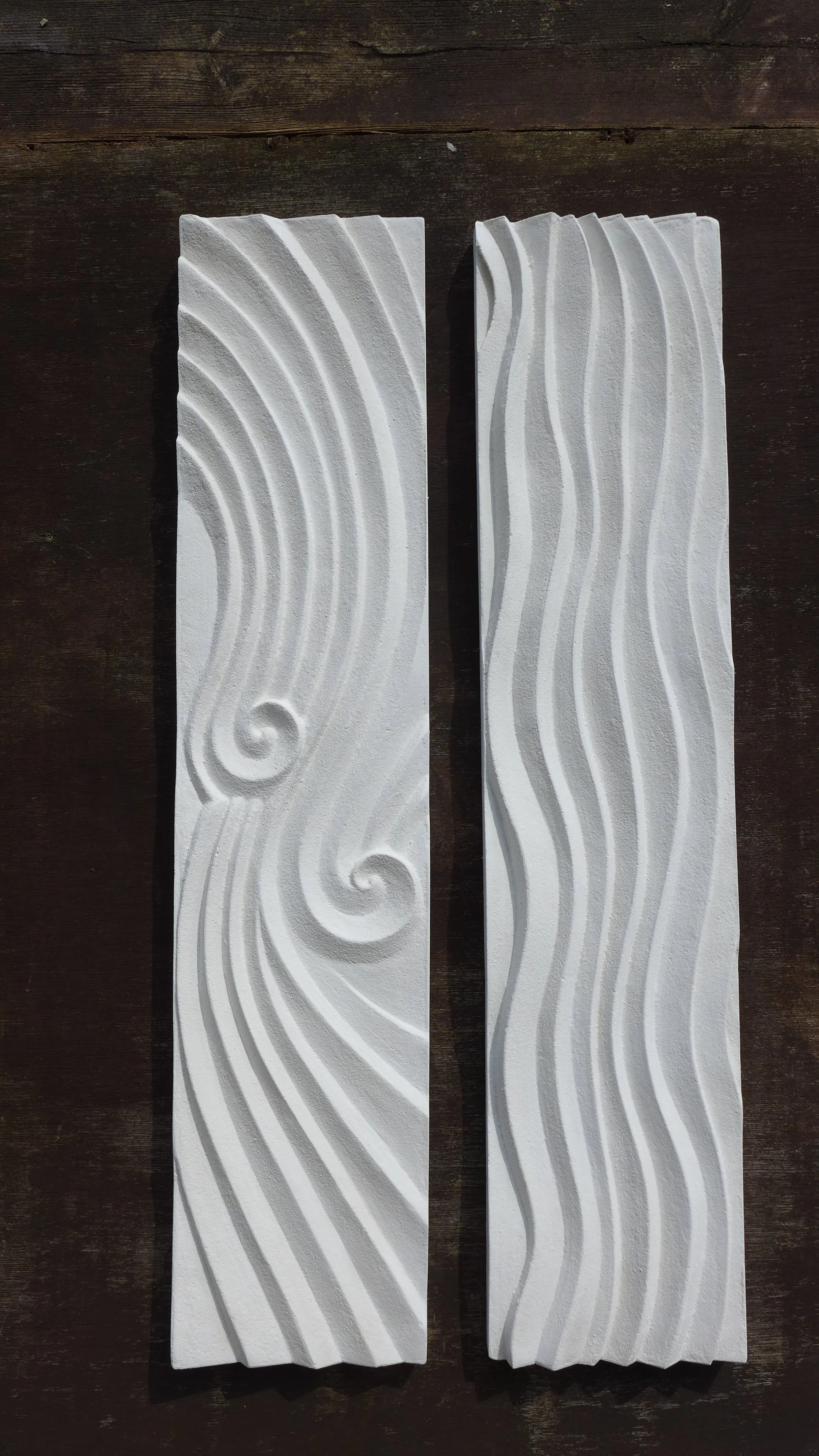 Two tall white Deco Dune Ripple panels on dark timber, one with spirals and one with flowing waves.