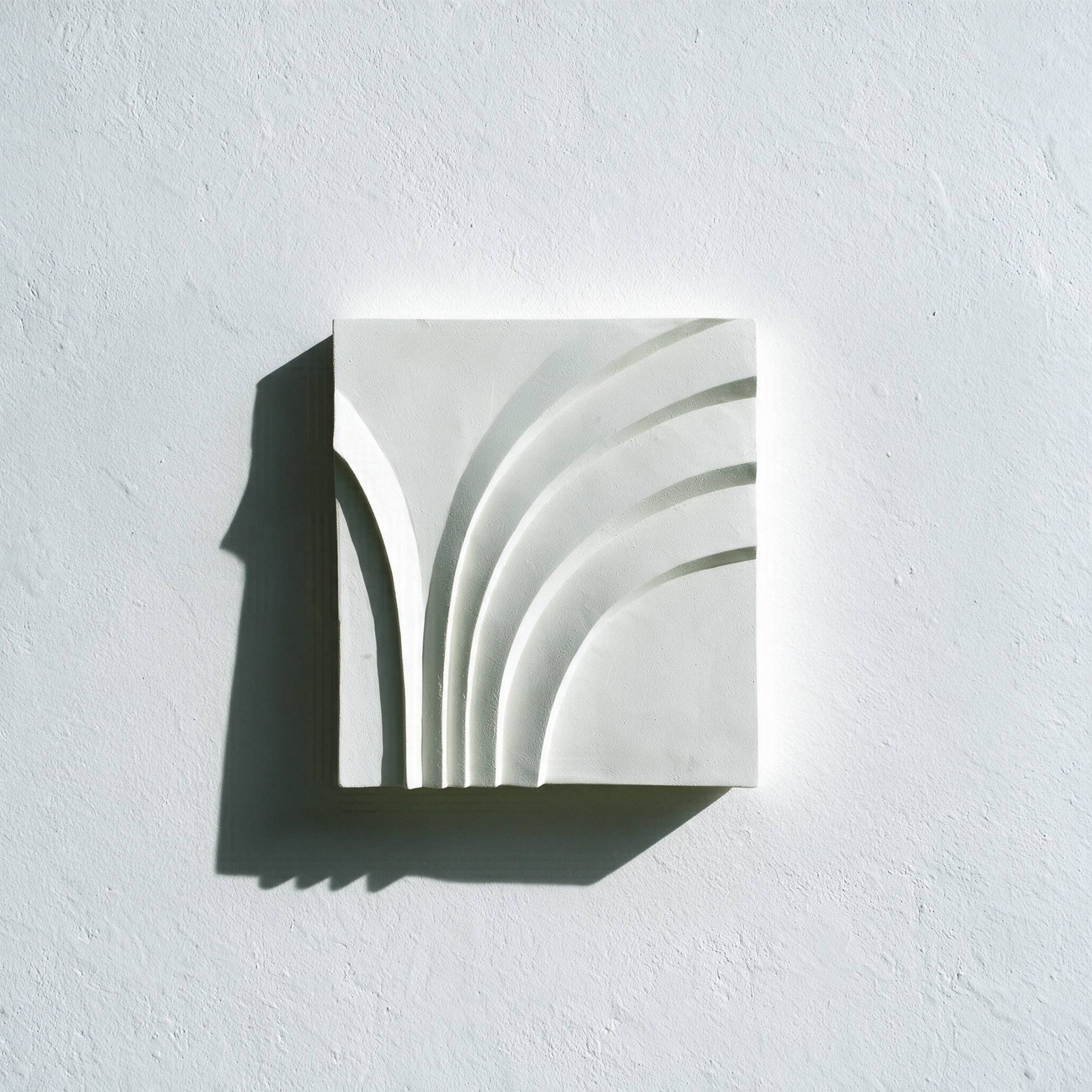 White Deco Palm and Spiral Palm 2 relief with spreading curved bands against a pale wall.