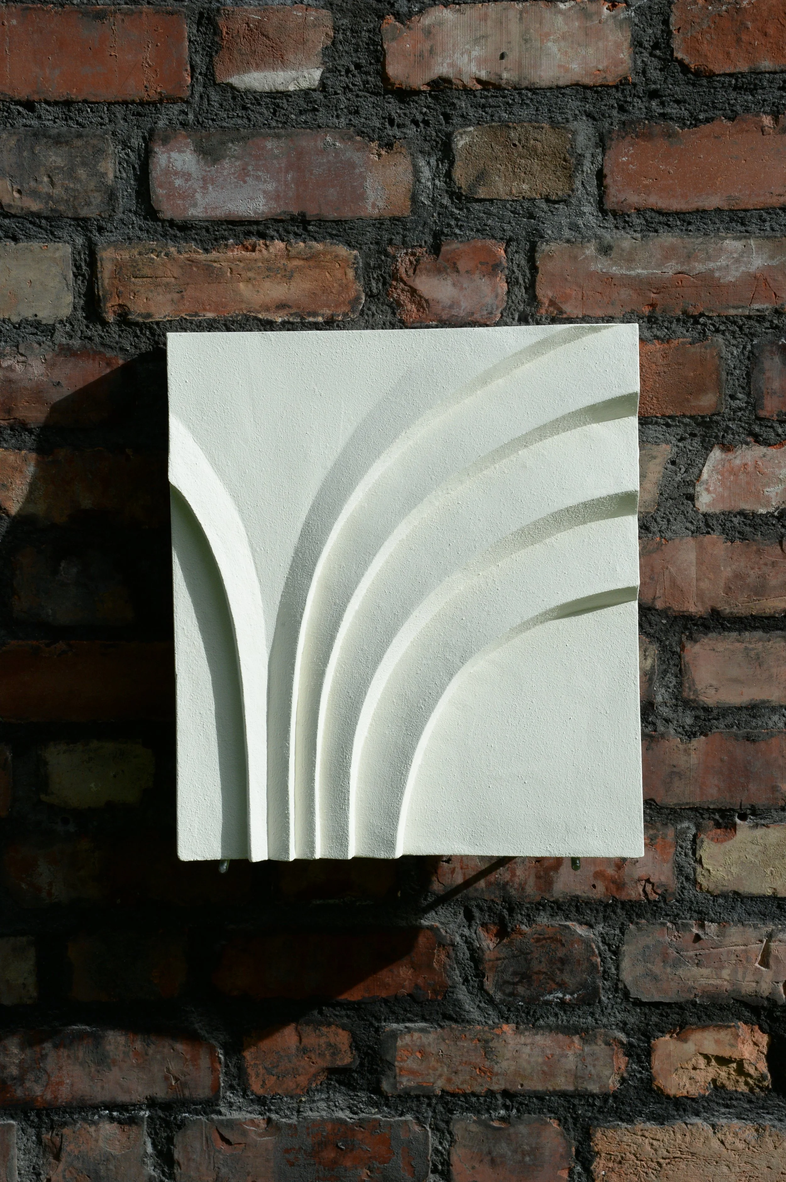 White Deco Palm and Spiral Palm 2 panel on a brick wall, shown in strong sunlight.