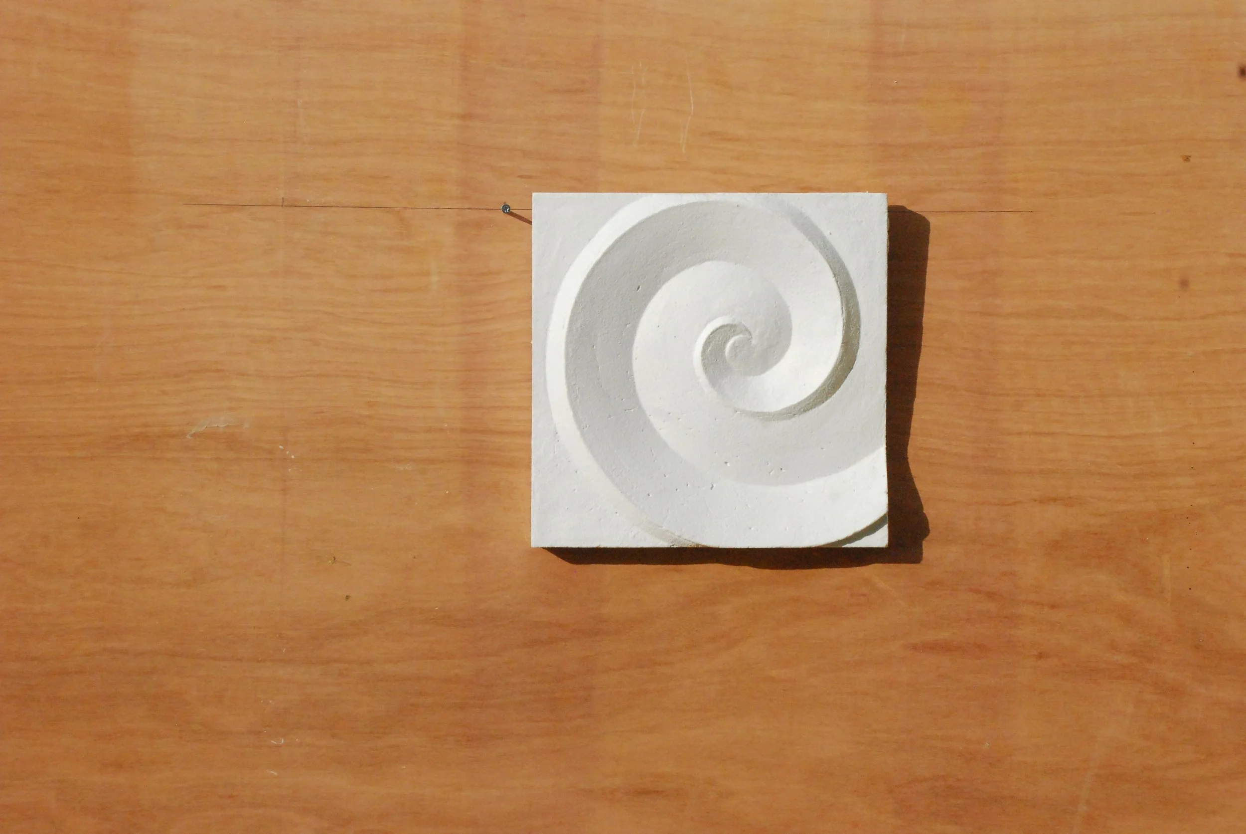 White Deco Palm and Spiral Spiral 2 relief displayed on a timber board.