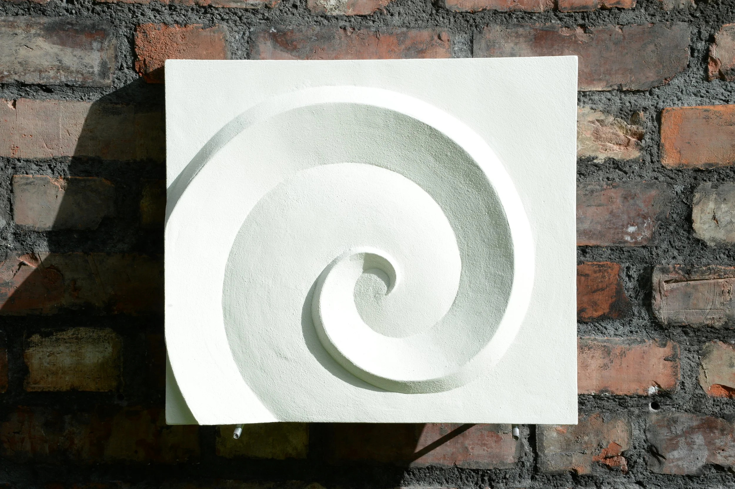 White Deco Palm and Spiral Spiral 2 relief on brick, with a broad curled ridge.