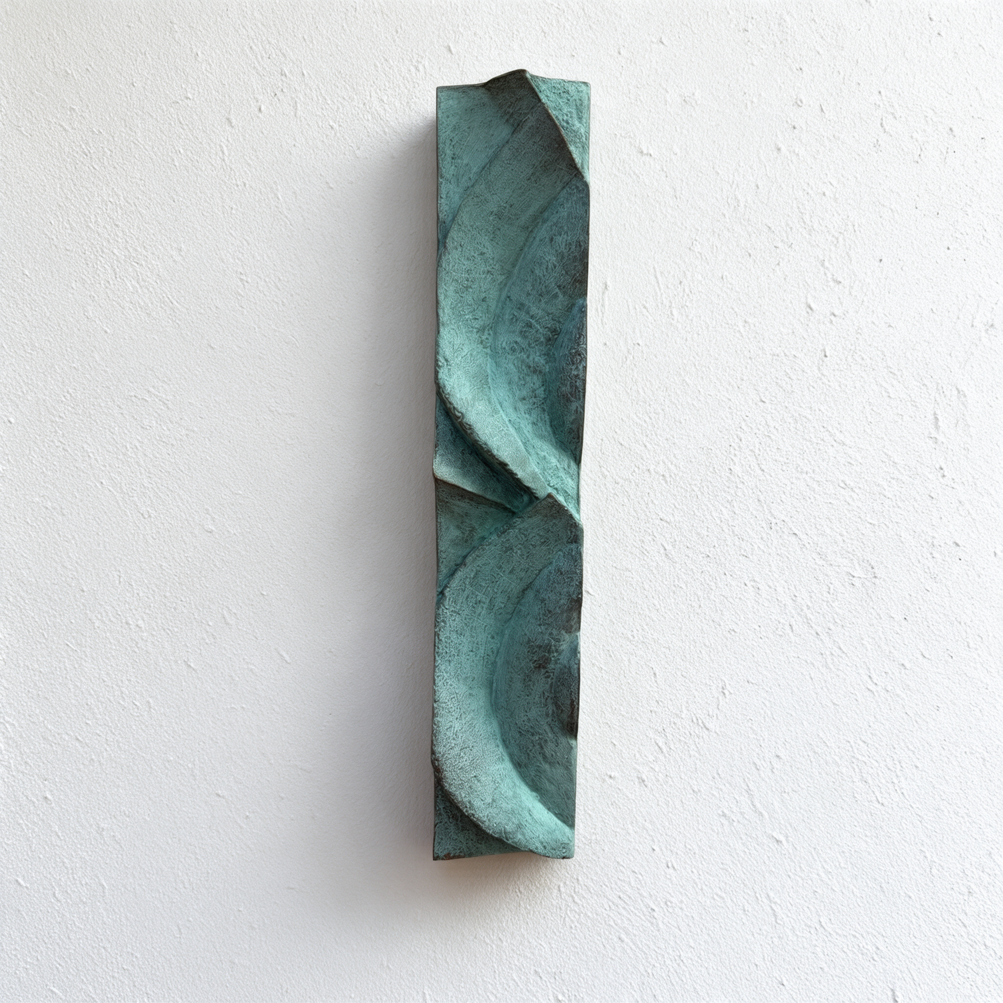 Tall verdigris Decowaves 1 relief with broad curved forms against a white wall.