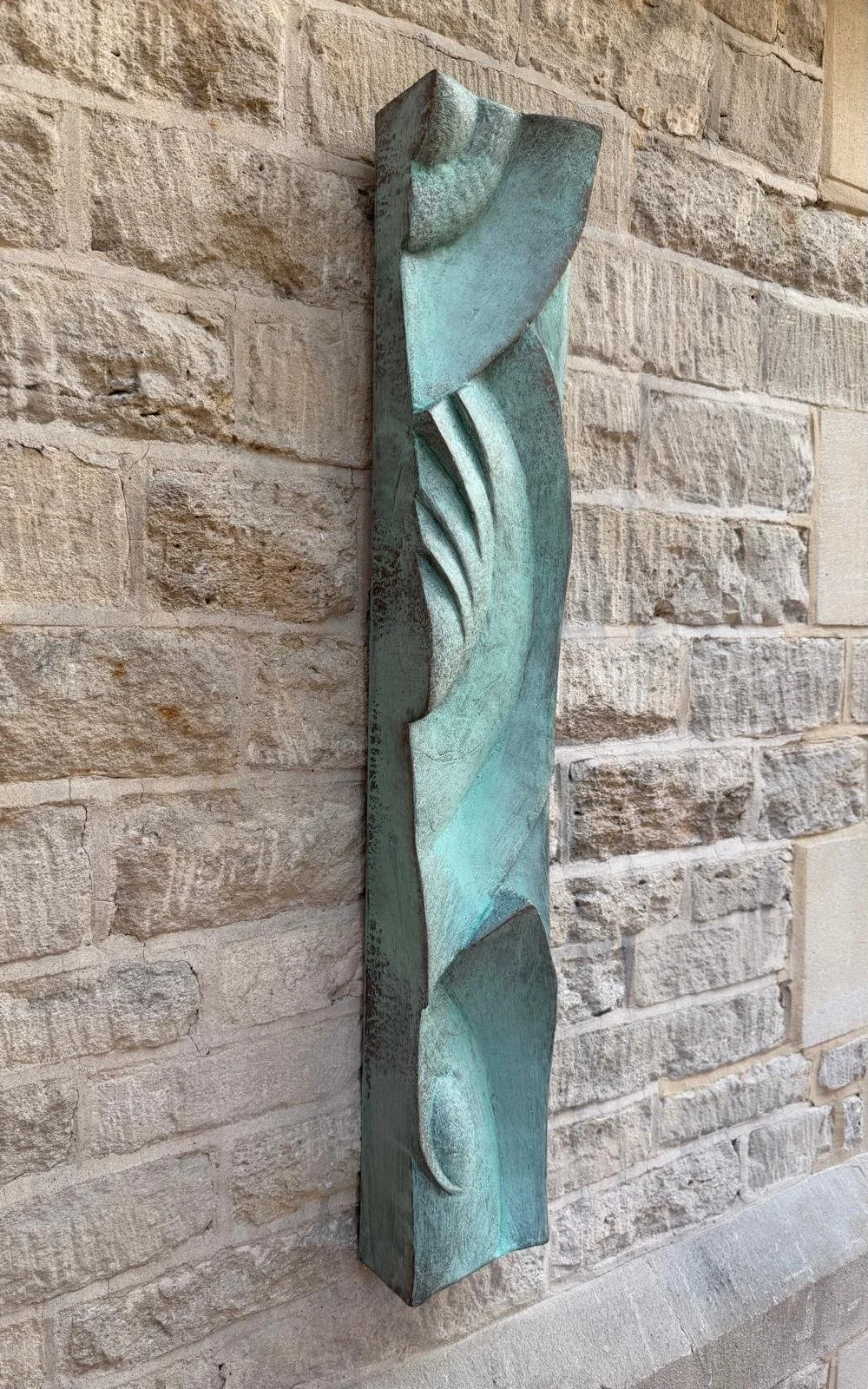 Angled view of the verdigris Decowaves 2 relief mounted vertically on stone.