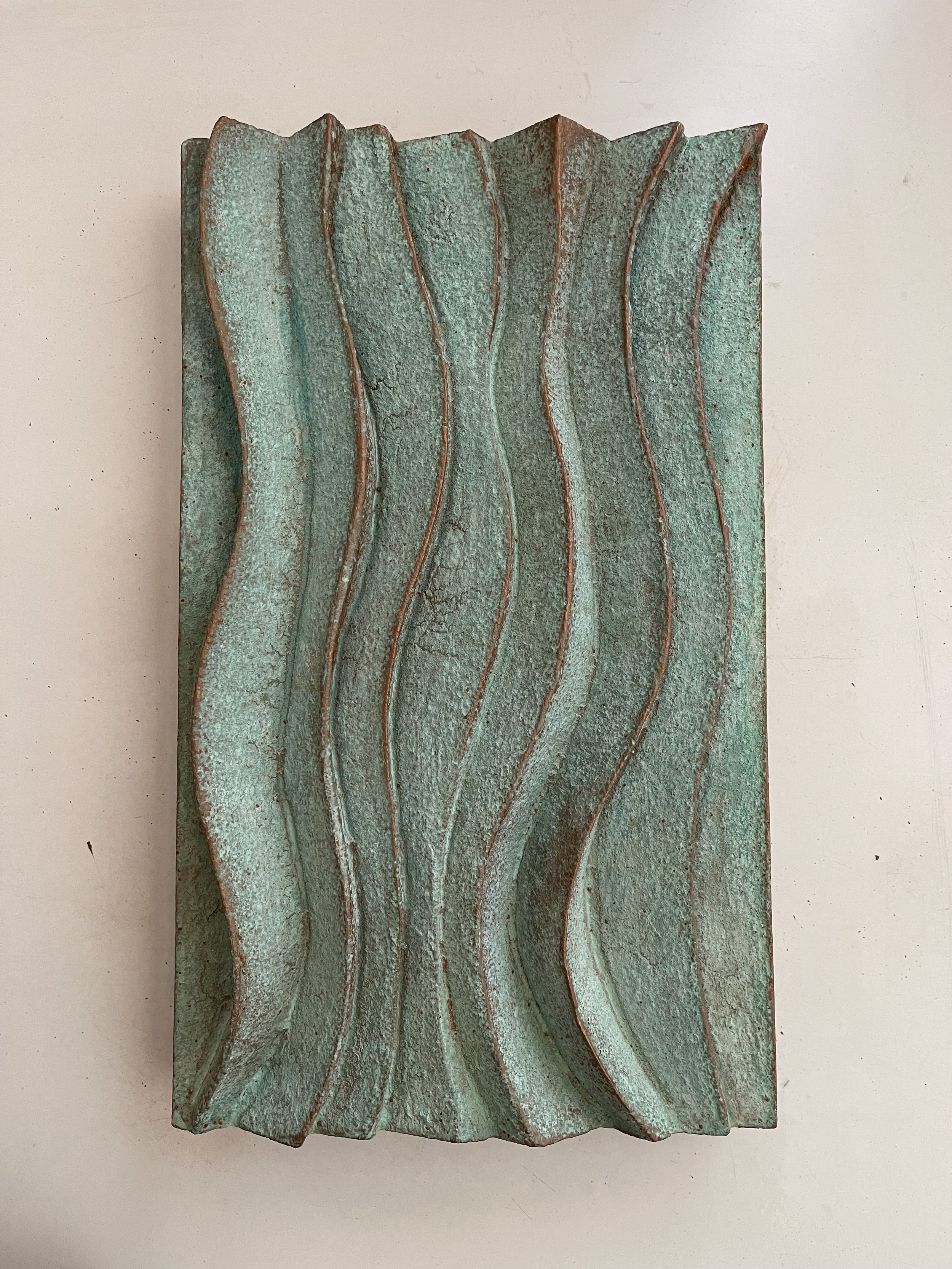 Verdigris Dune Ripple 1 relief with rippling blue-green ridges against a pale wall.