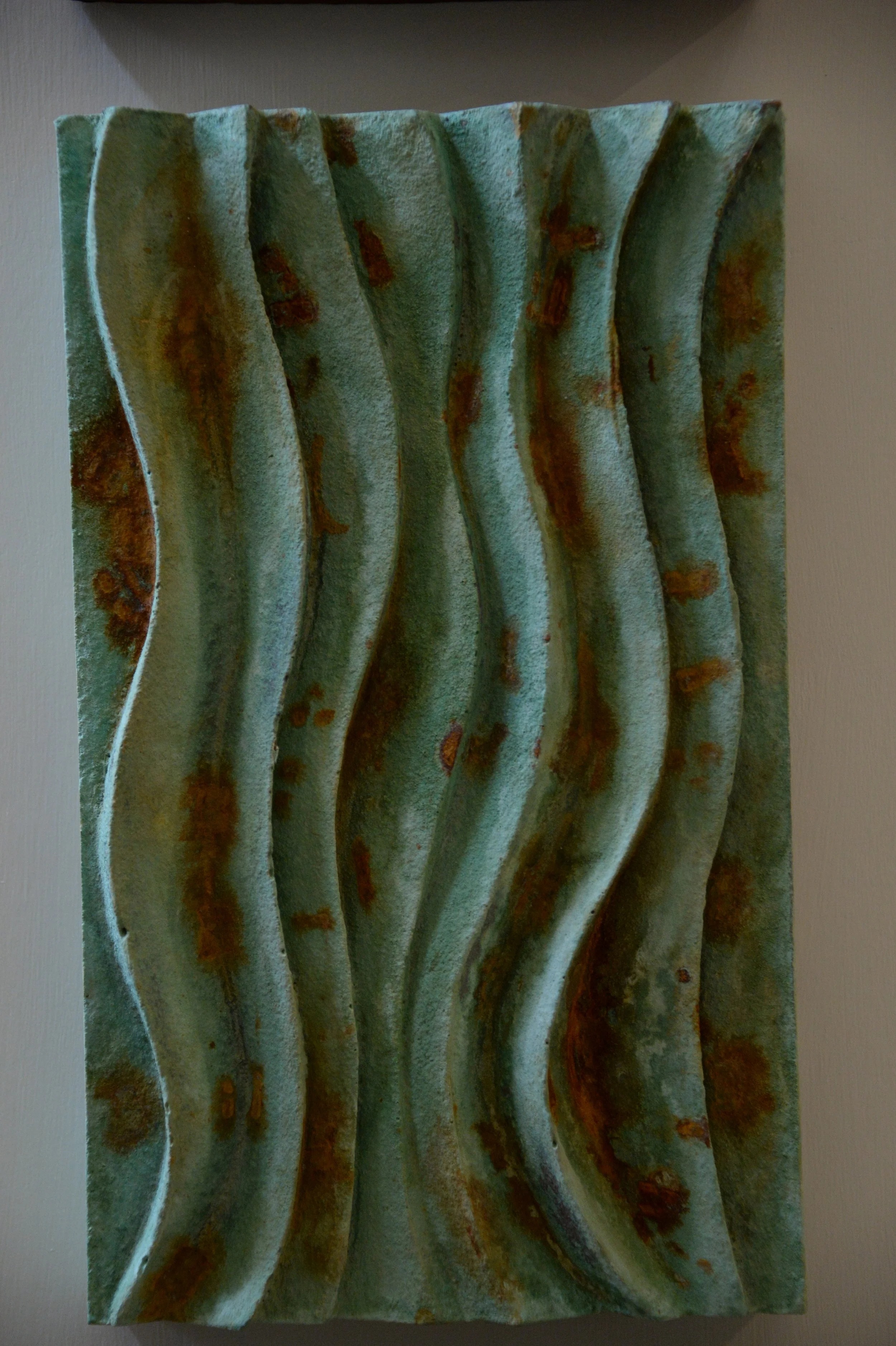 Close view of the verdigris and rust Dune Ripple 1 panel, with shadowed vertical waves.