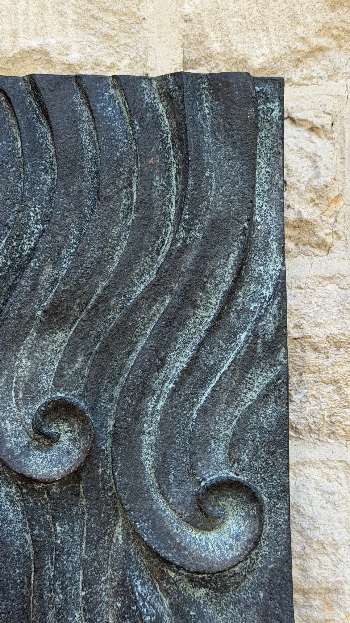 Close-up of the bronze and verdigris Dune Ripple relief, with two spirals and sweeping ridges.