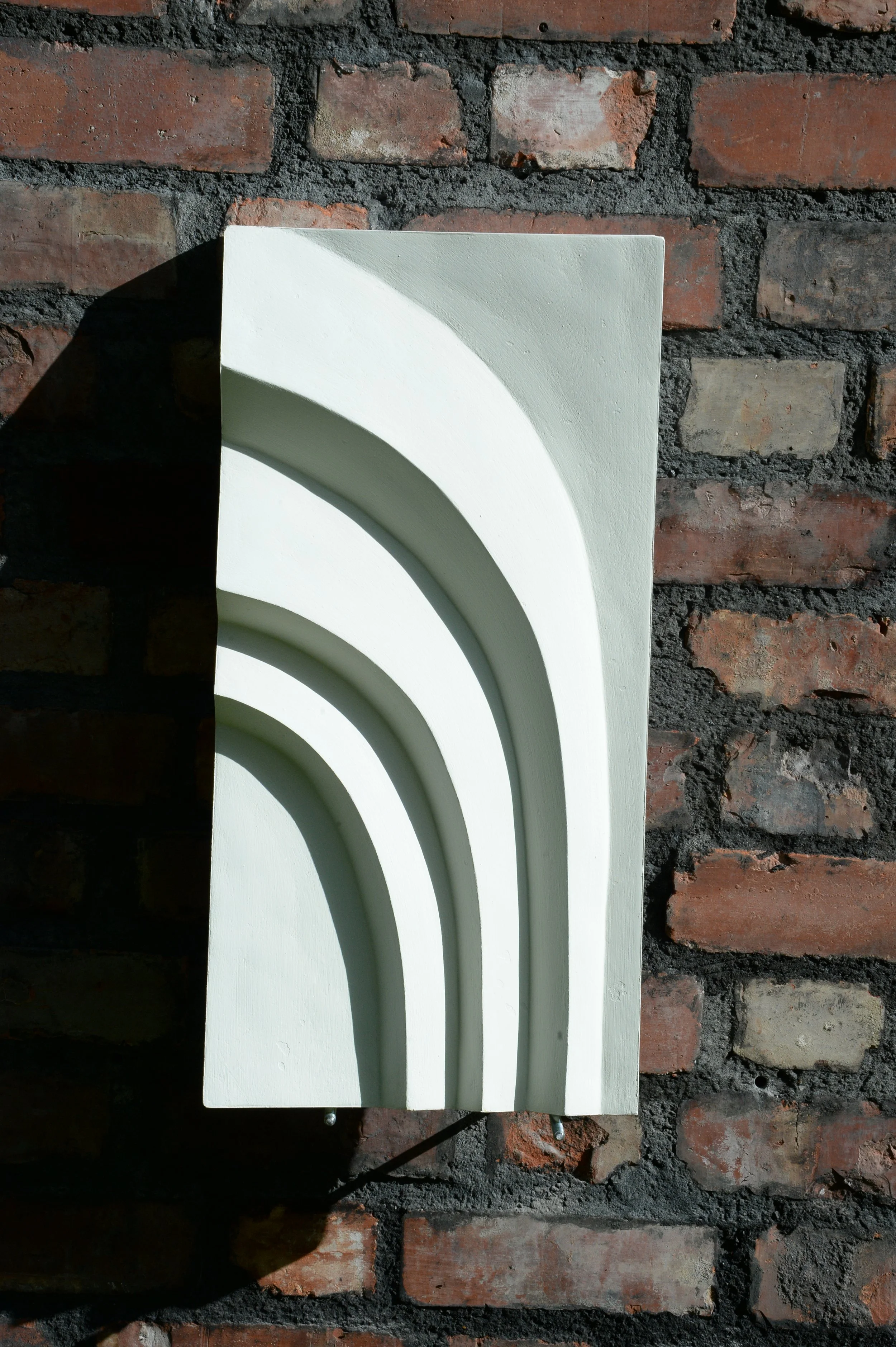 White Egyptian Palm 1 relief mounted vertically on brick.