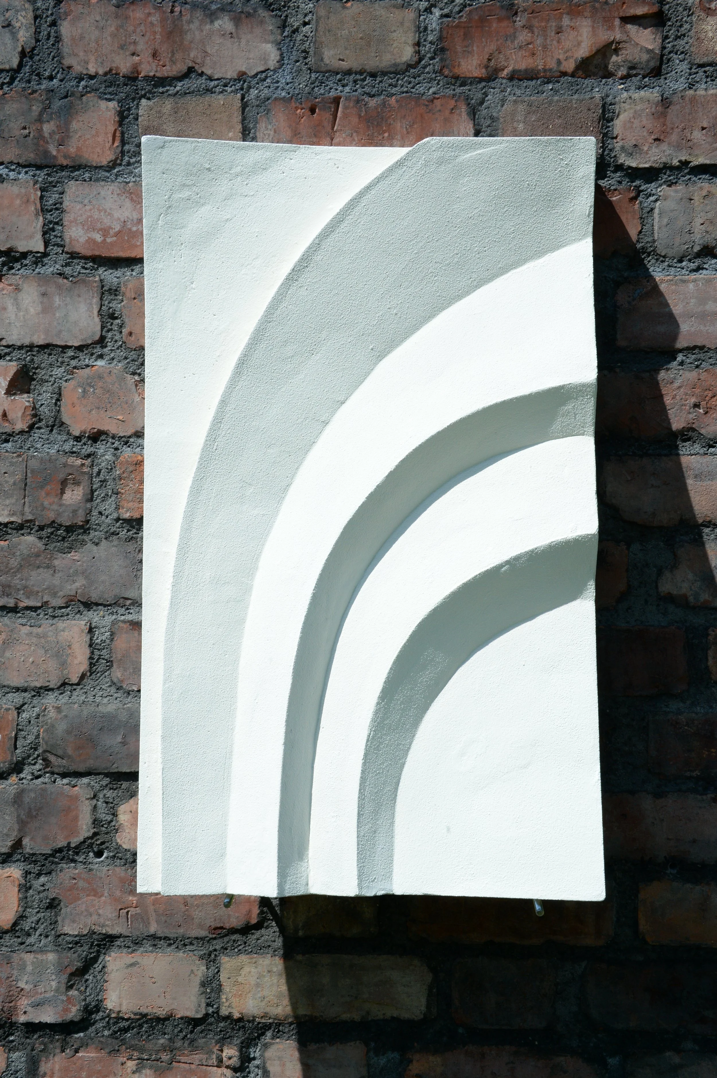 Angled view of white Egyptian Palm 3 Three Leaves on a brick wall.