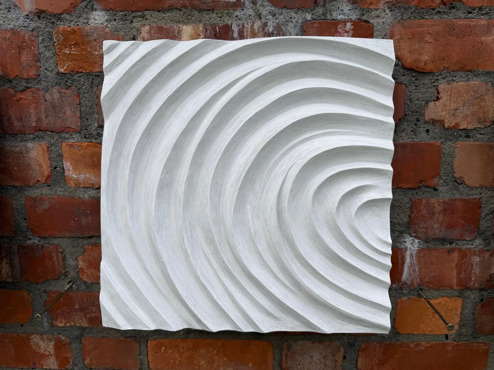 White Fingerprint Concentric 2 on brick, with ridges curving towards the right edge.