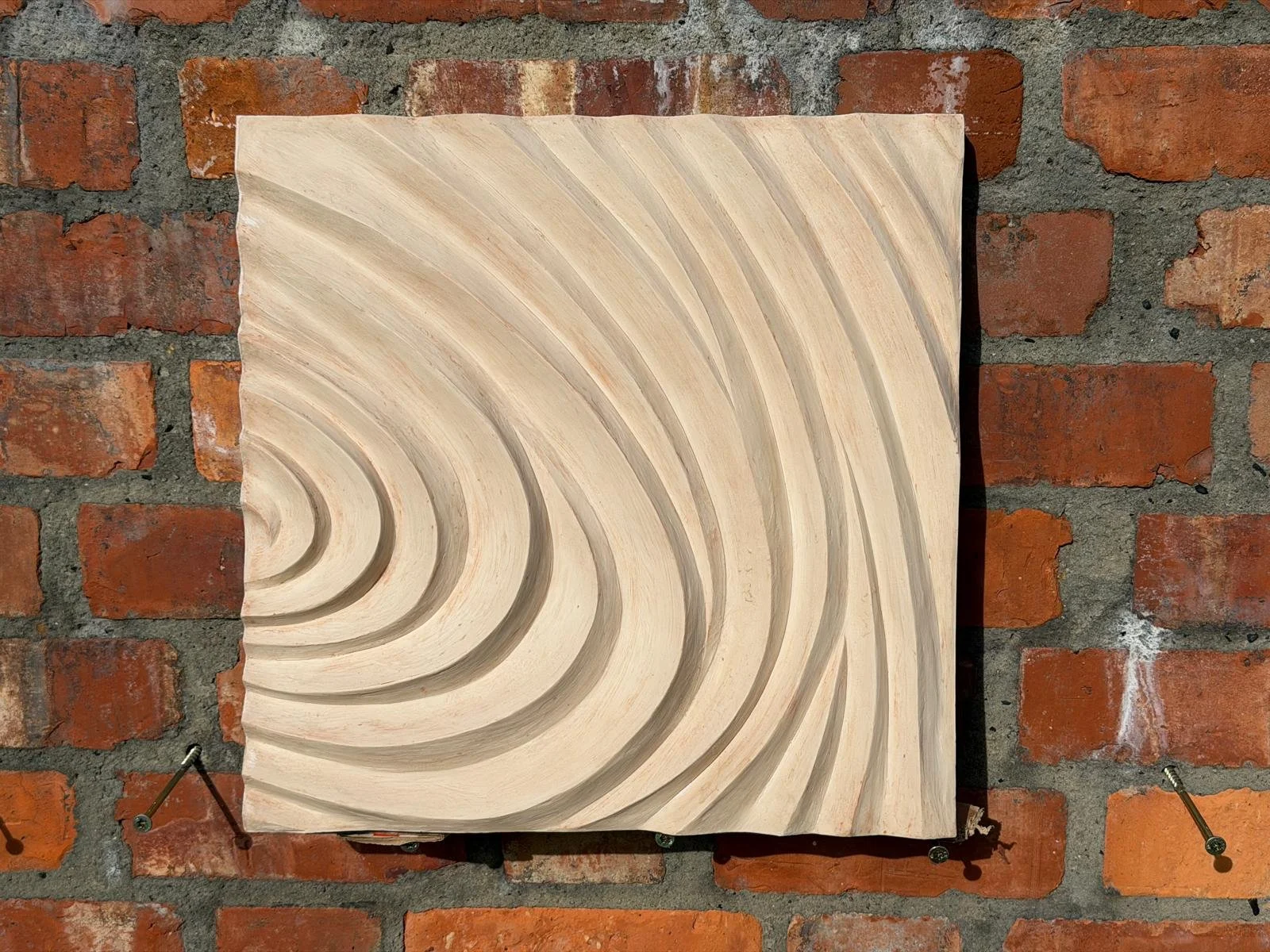 Cream Fingerprint Concentric 3 on brick, with ridges curving towards the left edge.