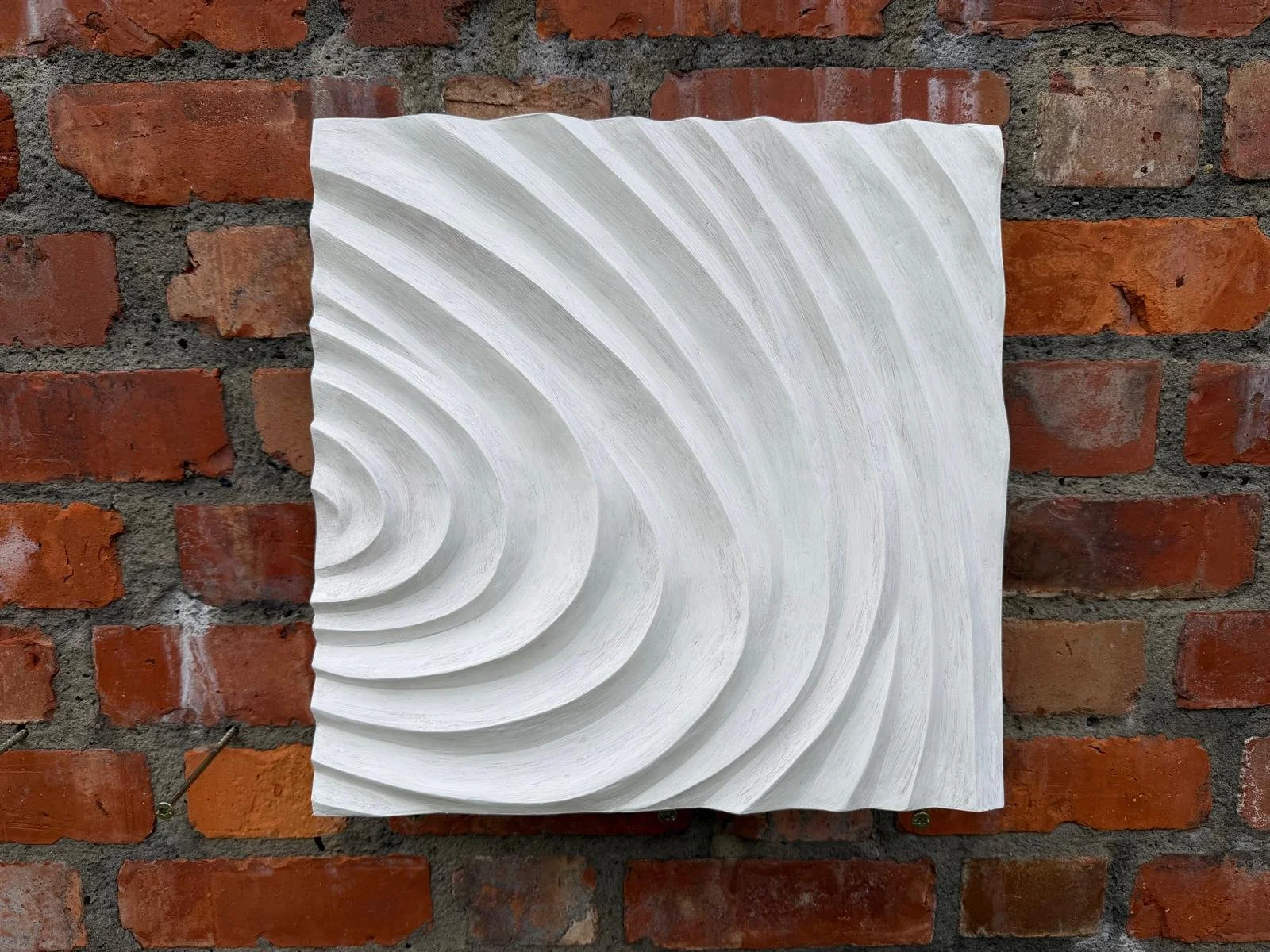 White Fingerprint Concentric 3 on brick, with ridges curving towards the left edge.