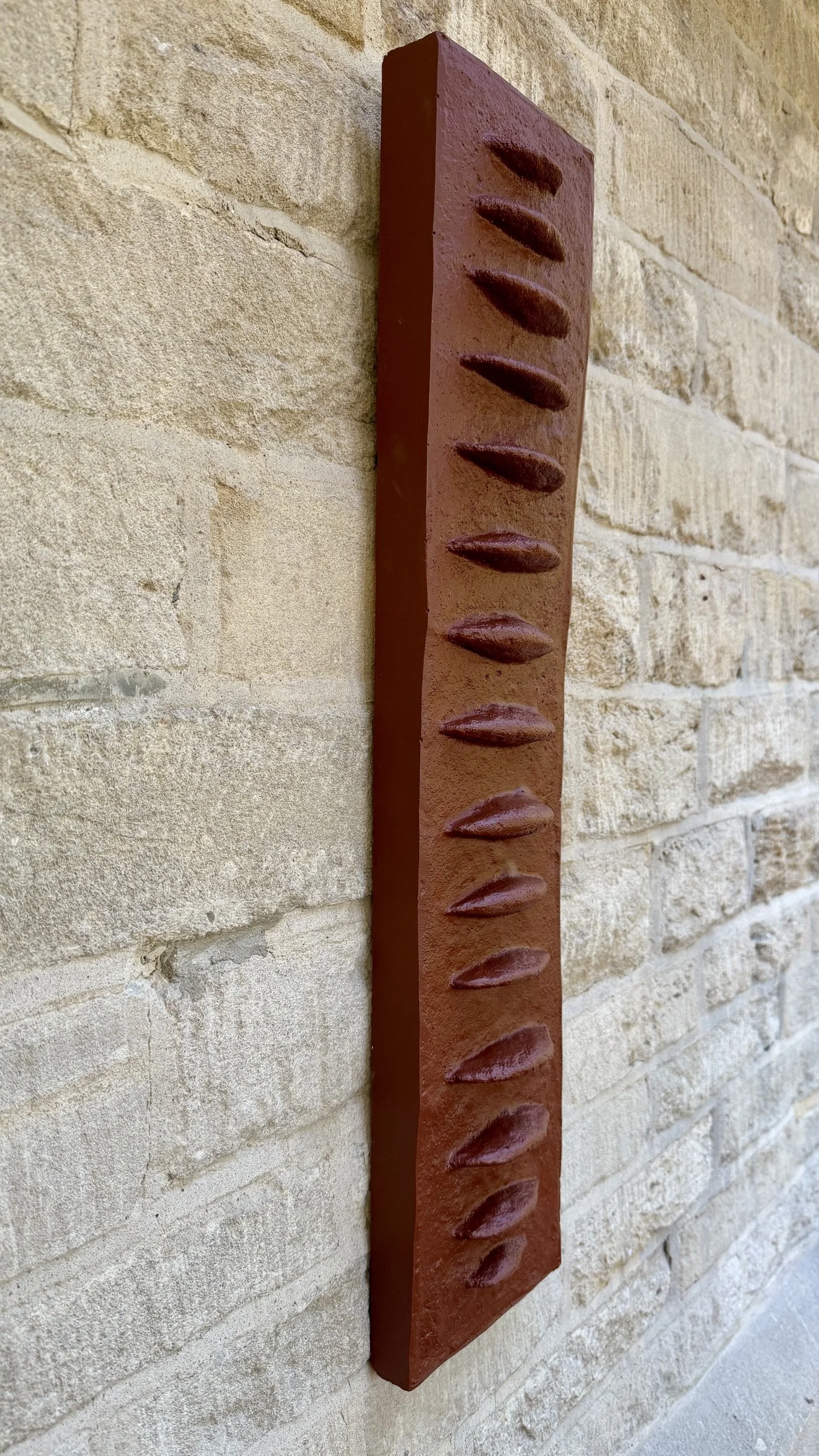 Angled view of terracotta Frozen Fish, showing the depth of its repeated raised forms.