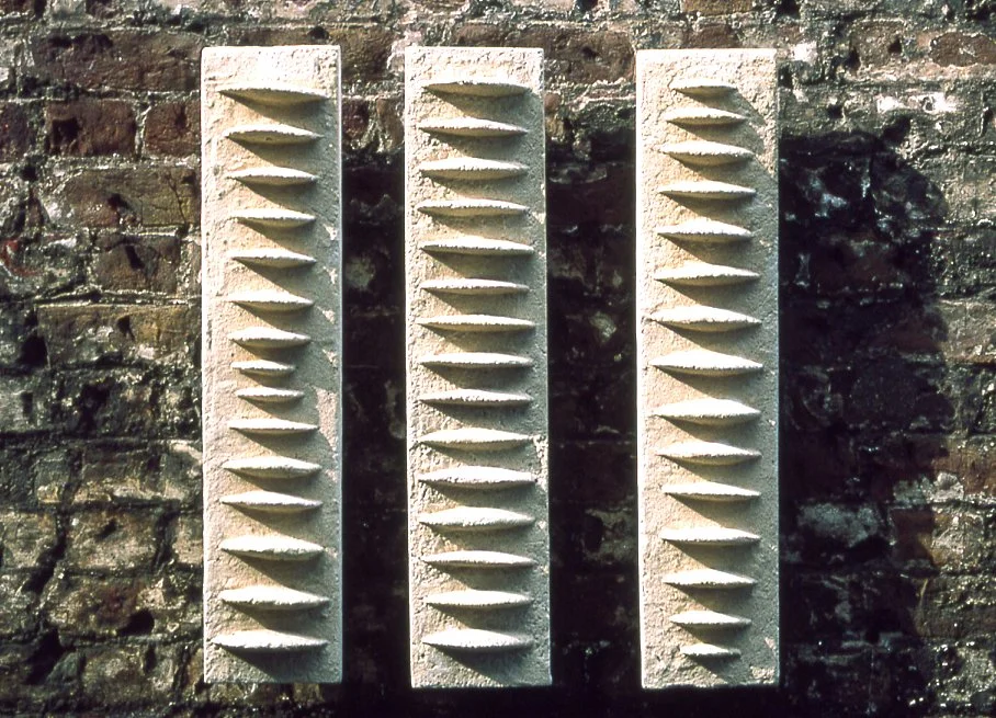 Three white Frozen Fish panels mounted side by side on a brick wall.