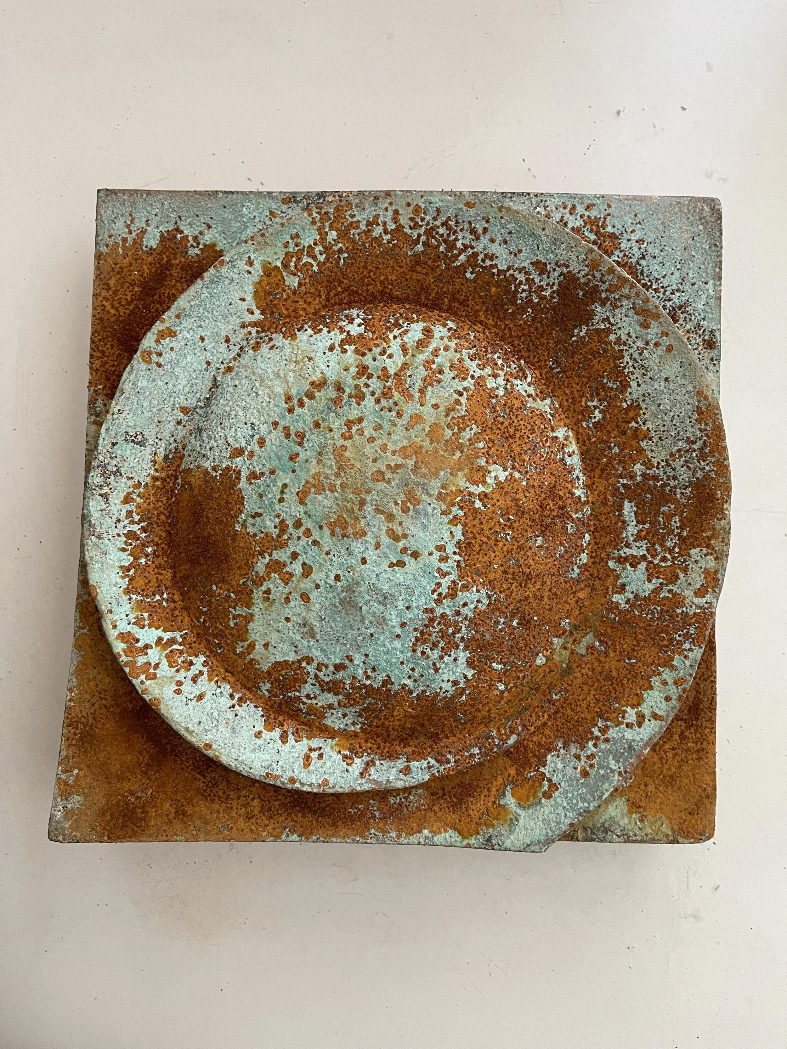 Verdigris and rust Moon Crater Phase 2 relief against a pale wall.