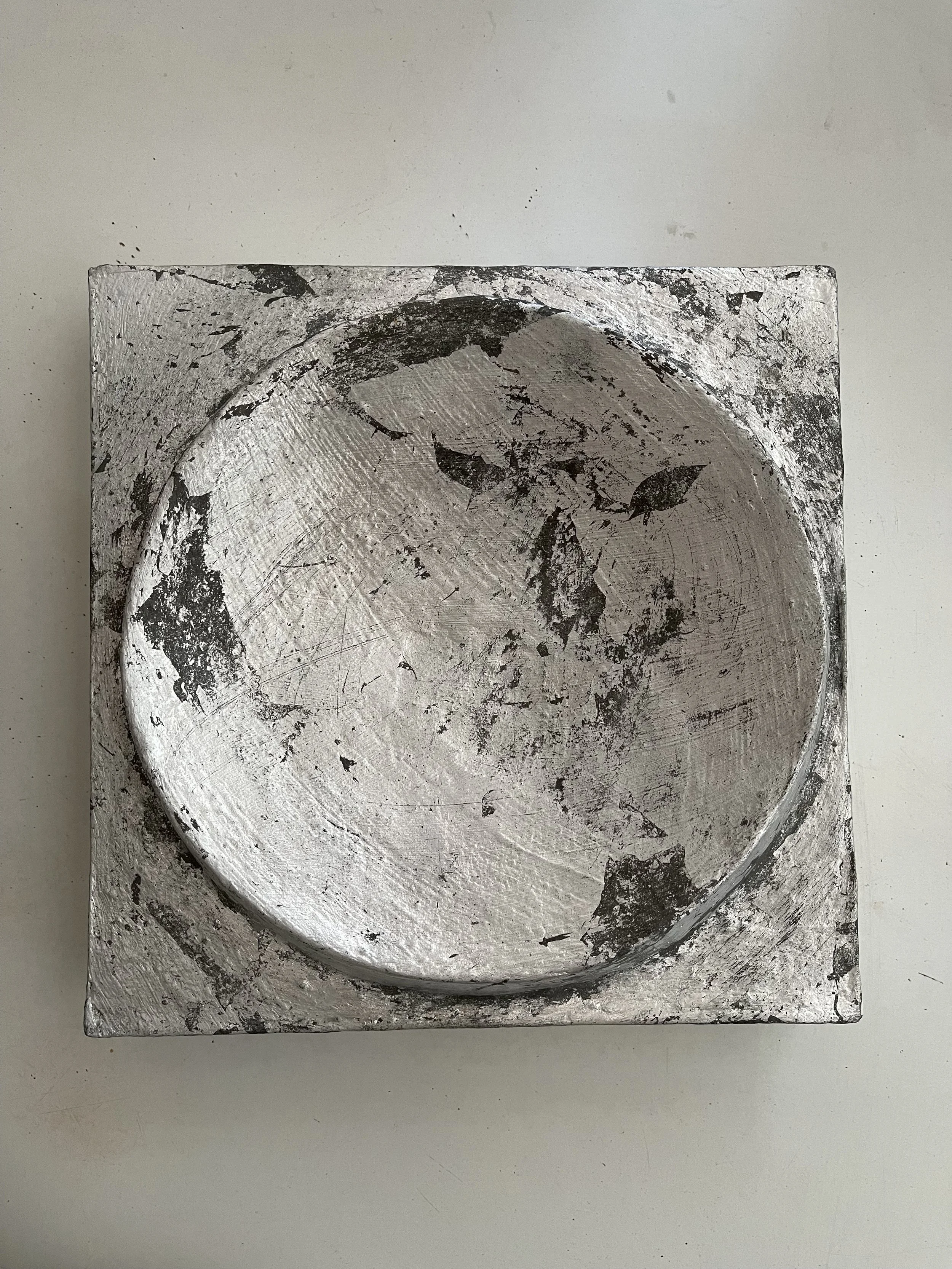 Angled view of the silver and bronze-coloured Moon Crater Phase 4 relief against a pale wall.