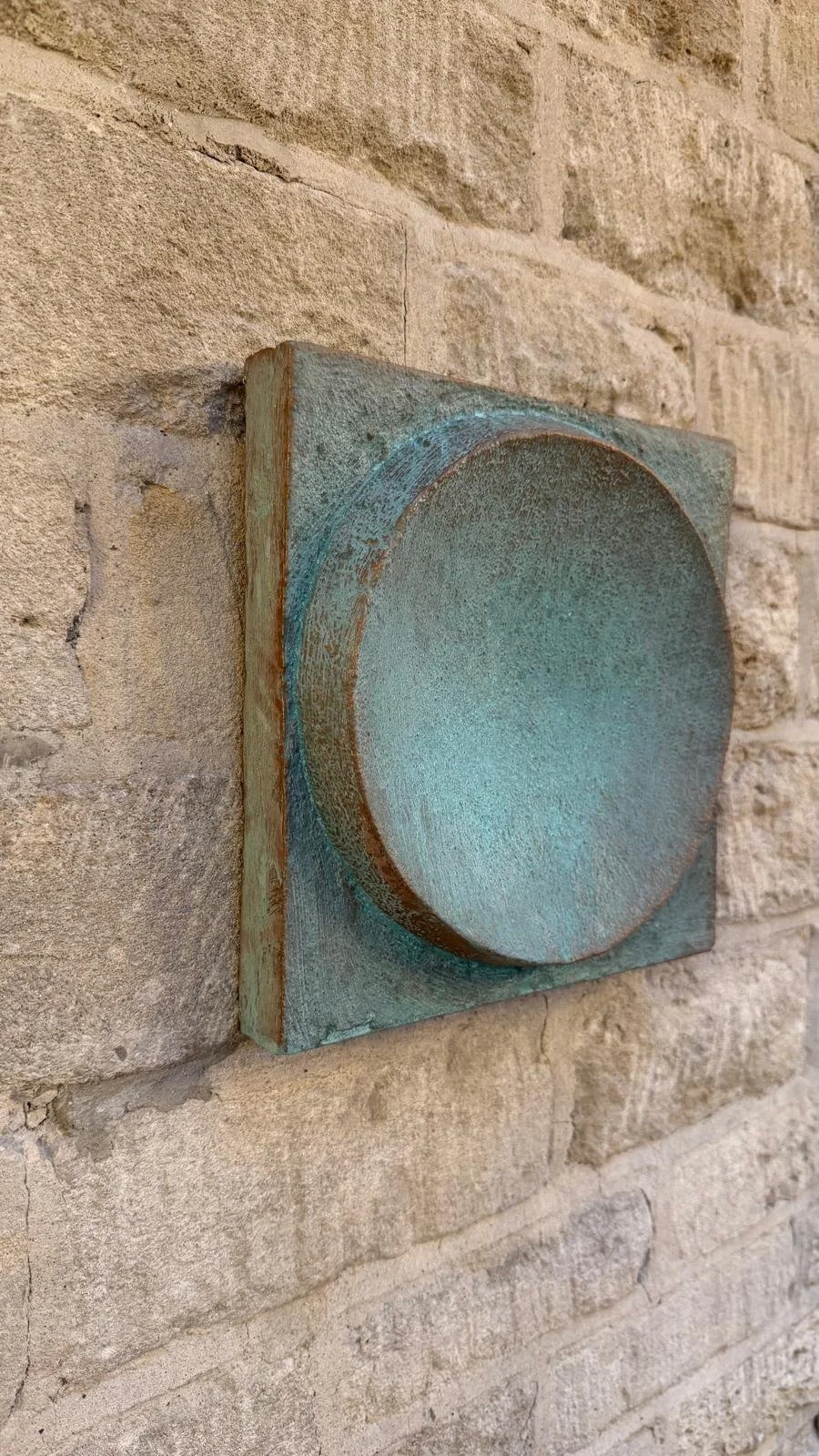 Side view of verdigris Moon Crater Phase 4 on a stone wall.