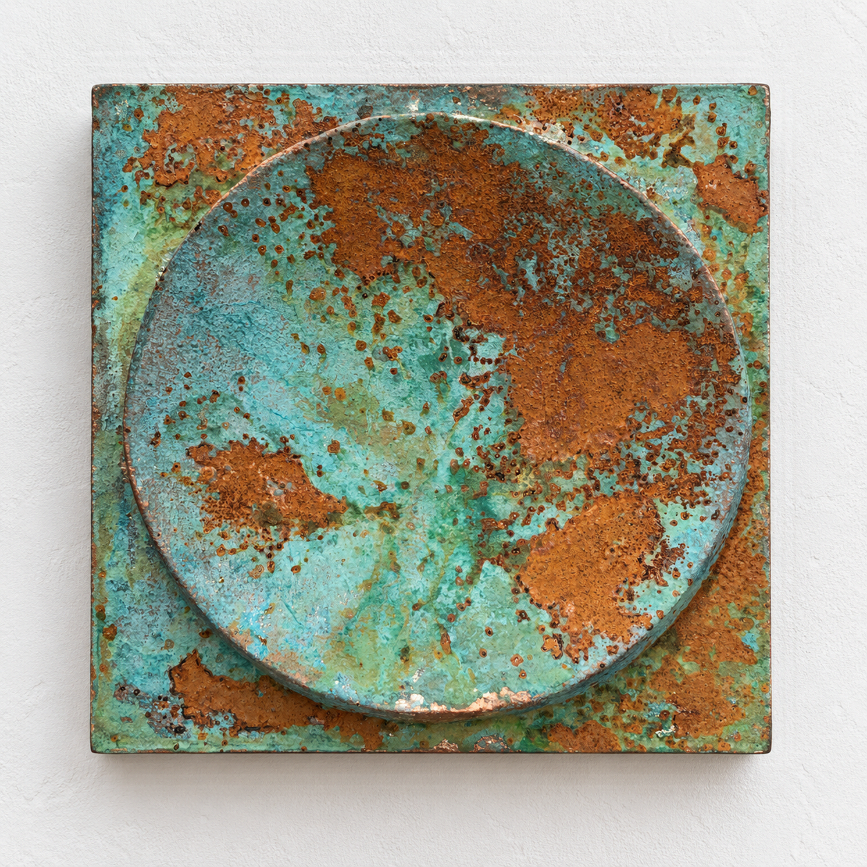 Verdigris and rust Moon Crater Phase 4 square relief with a circular bowl against white.